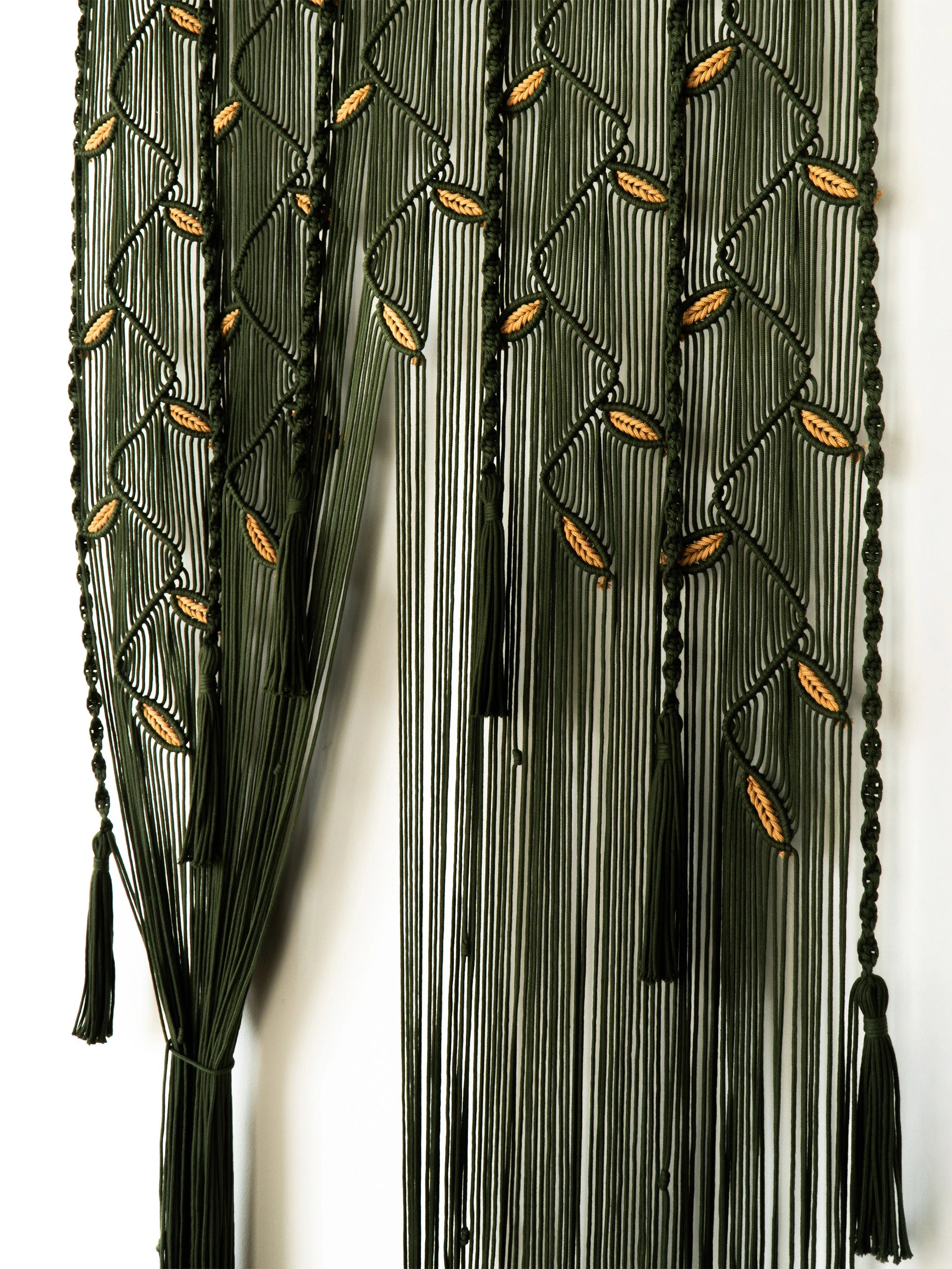A dark olive green beaded curtain featuring vertical strands, geometric diamond patterns, and small gold leaf accents, with tassel ends on a white background.