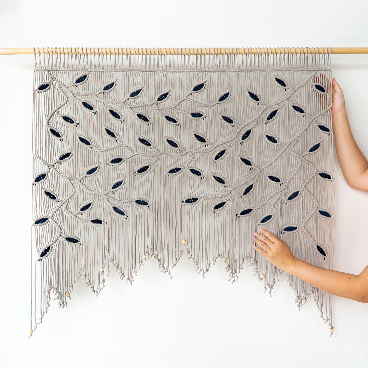 Handmade woven wall art with black patterns on a white background