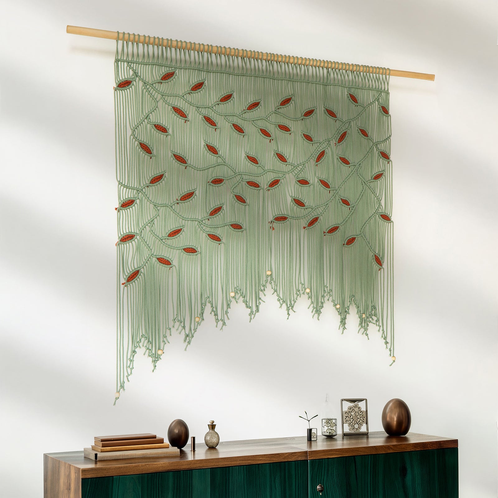 Decorative green woven wall hanging with red accents on a white wall above a wooden console table.