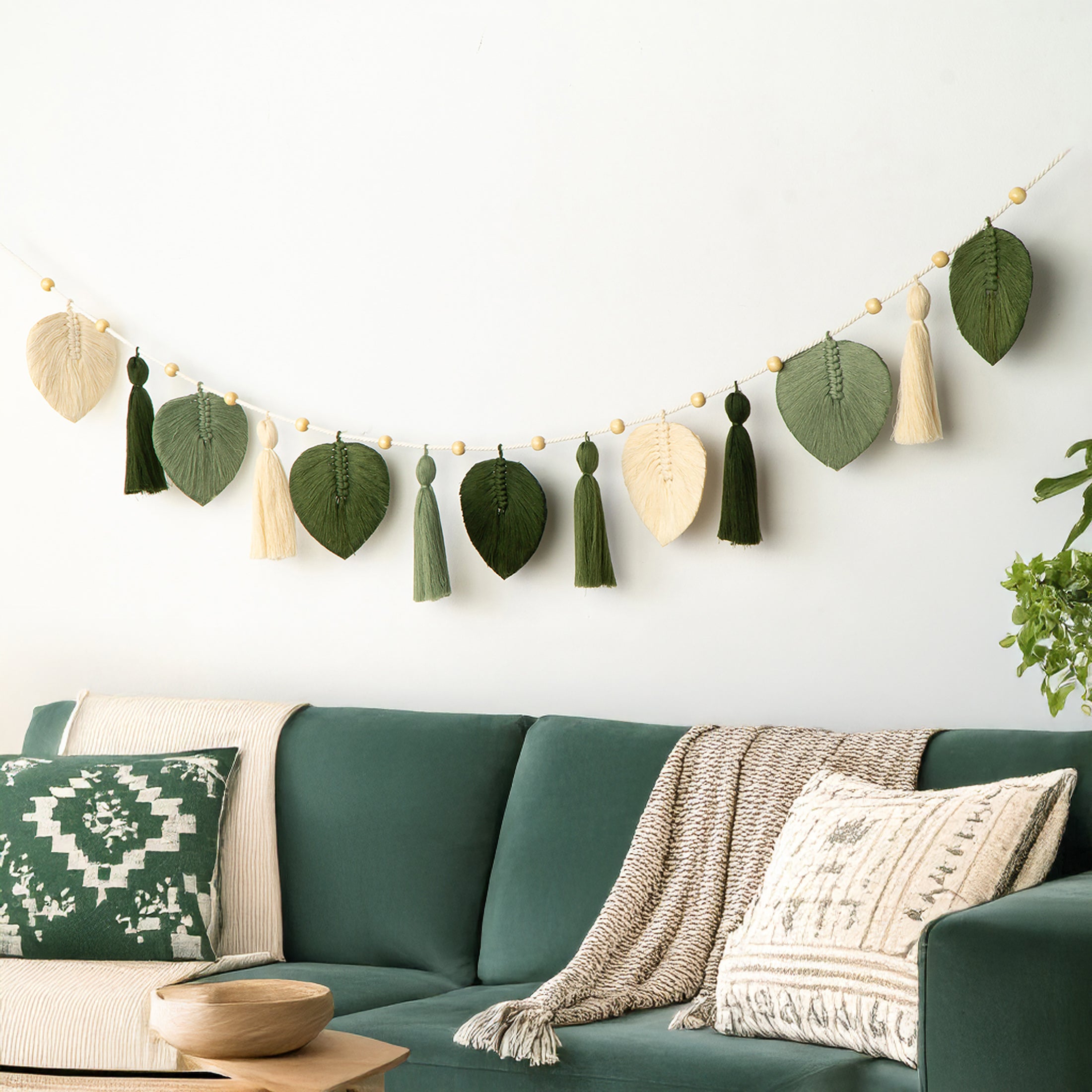 Two wall hangings with circular wooden bases and long string-like extensions on a white wall.