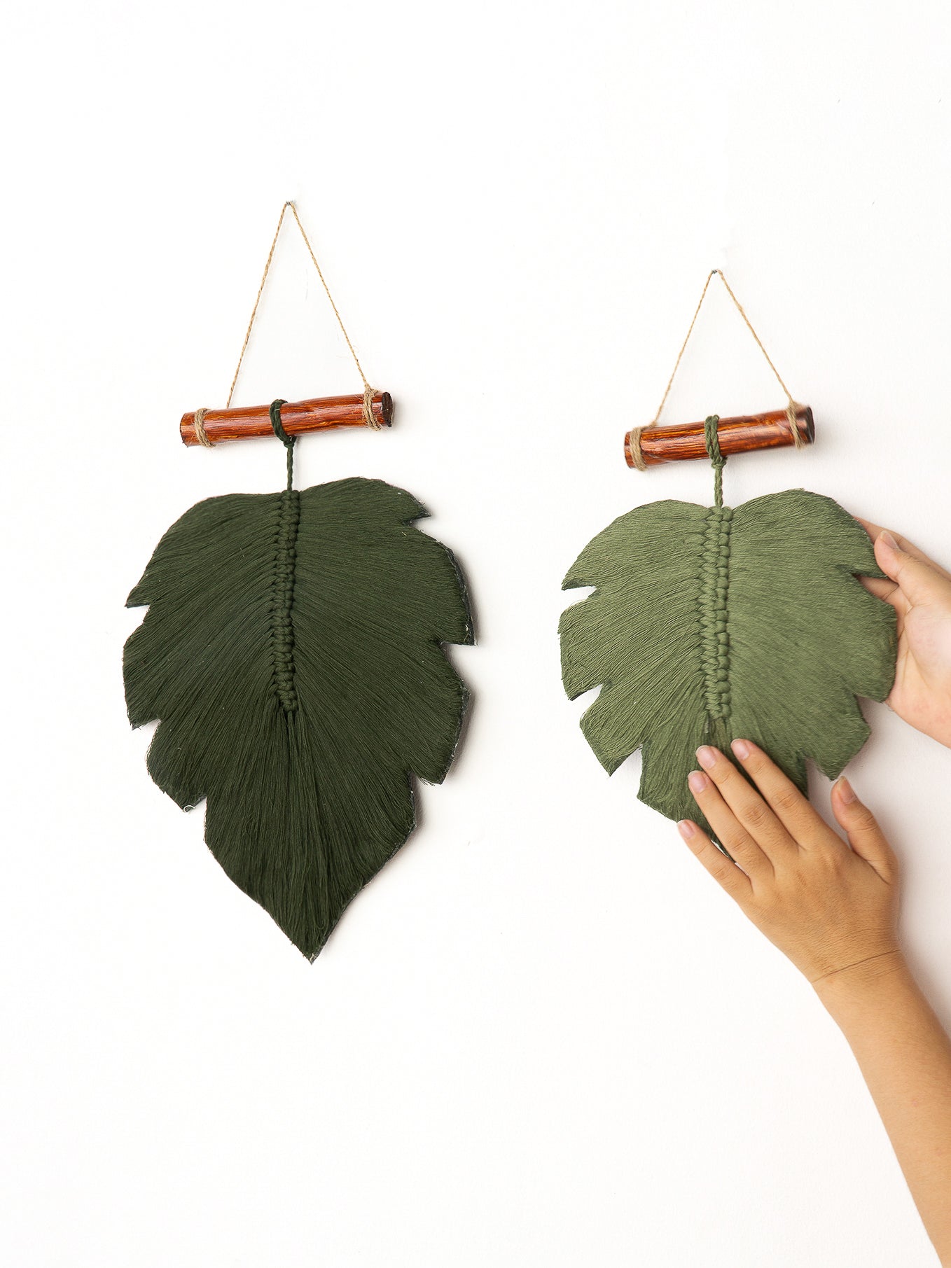Green leaf-shaped wall decor with wooden hooks on a white background