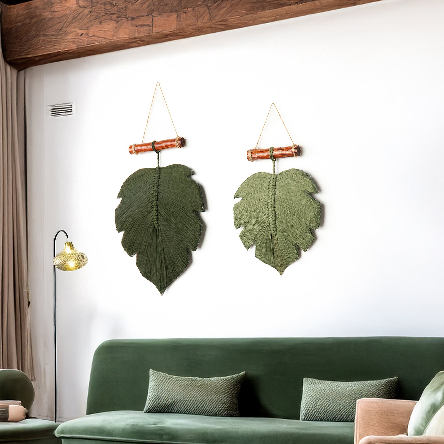 Two green leaf-shaped wall hangings on a white wall above a green sofa.