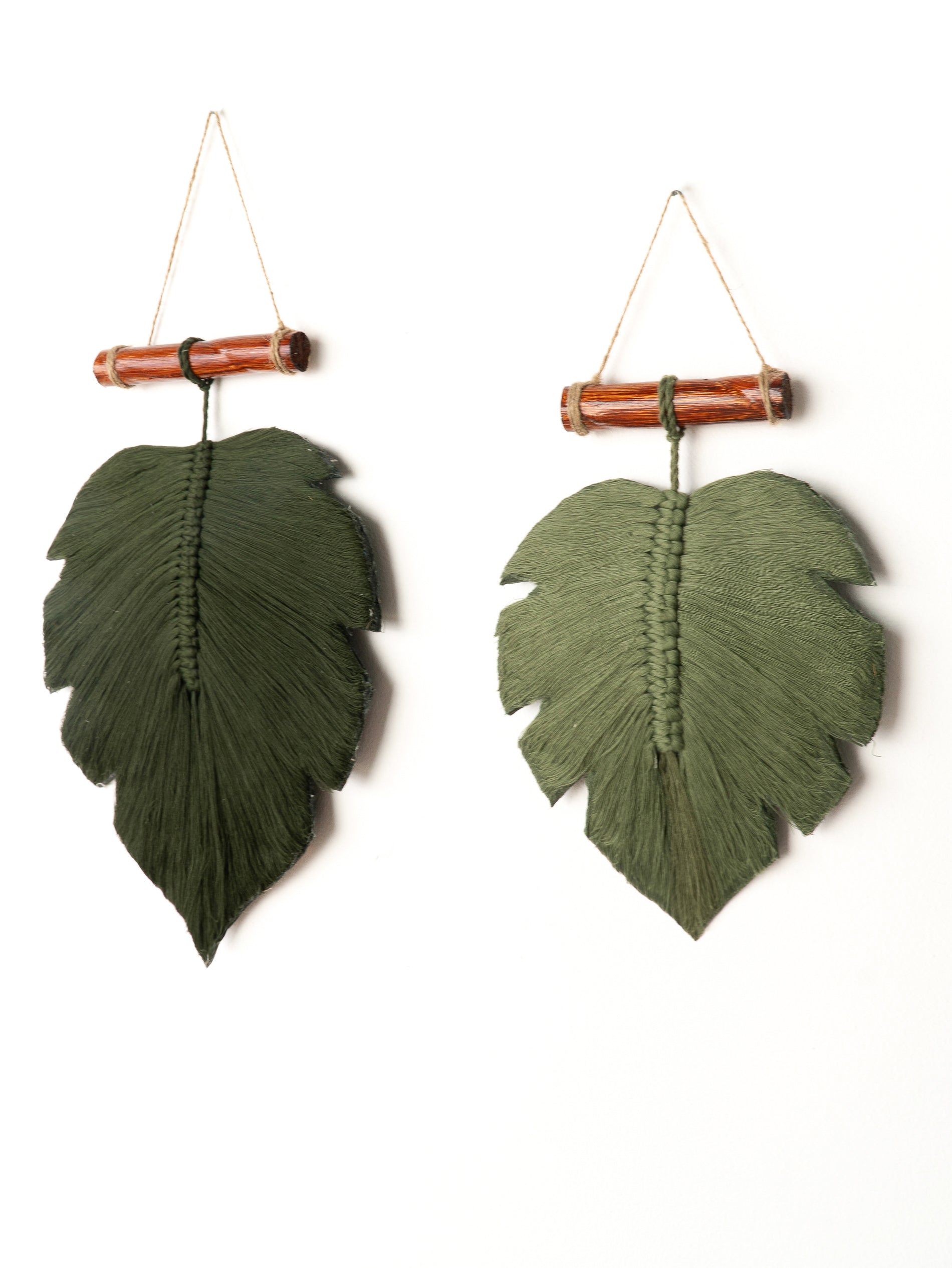 Two green leaf-shaped wall hangings with bamboo accents on a white background