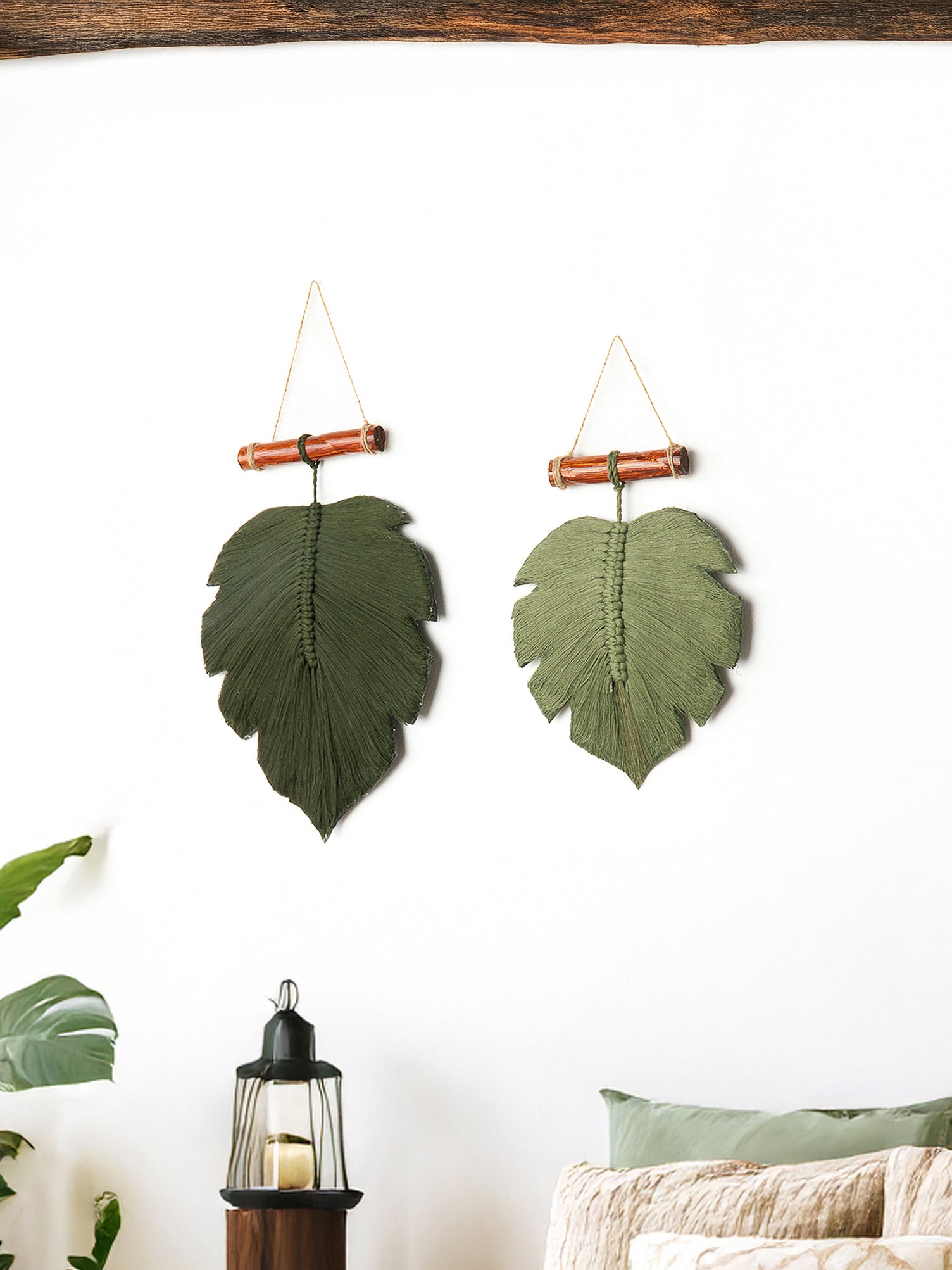 Two green leaf-shaped wall hangings on a white wall with a wooden frame.
