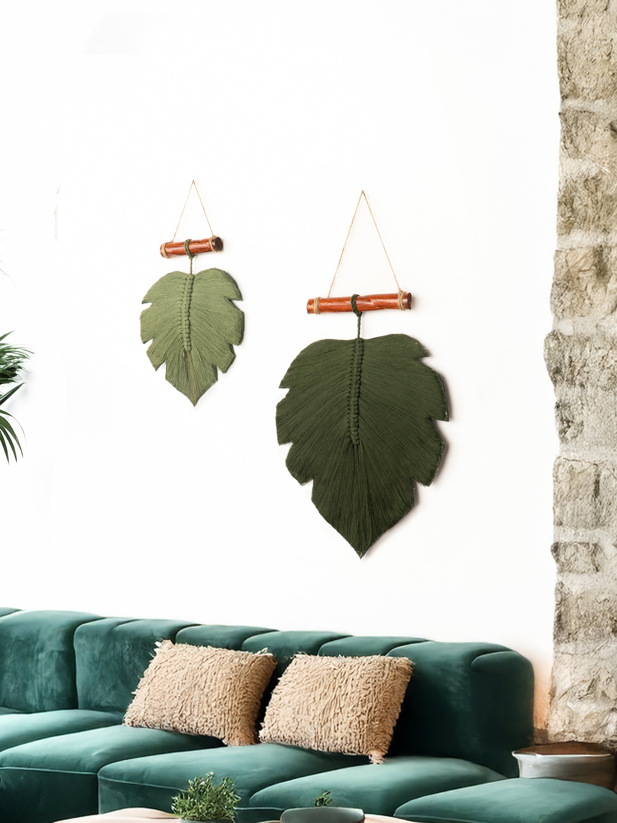 Decorative leaf wall hangings above a green sofa with textured cushions.