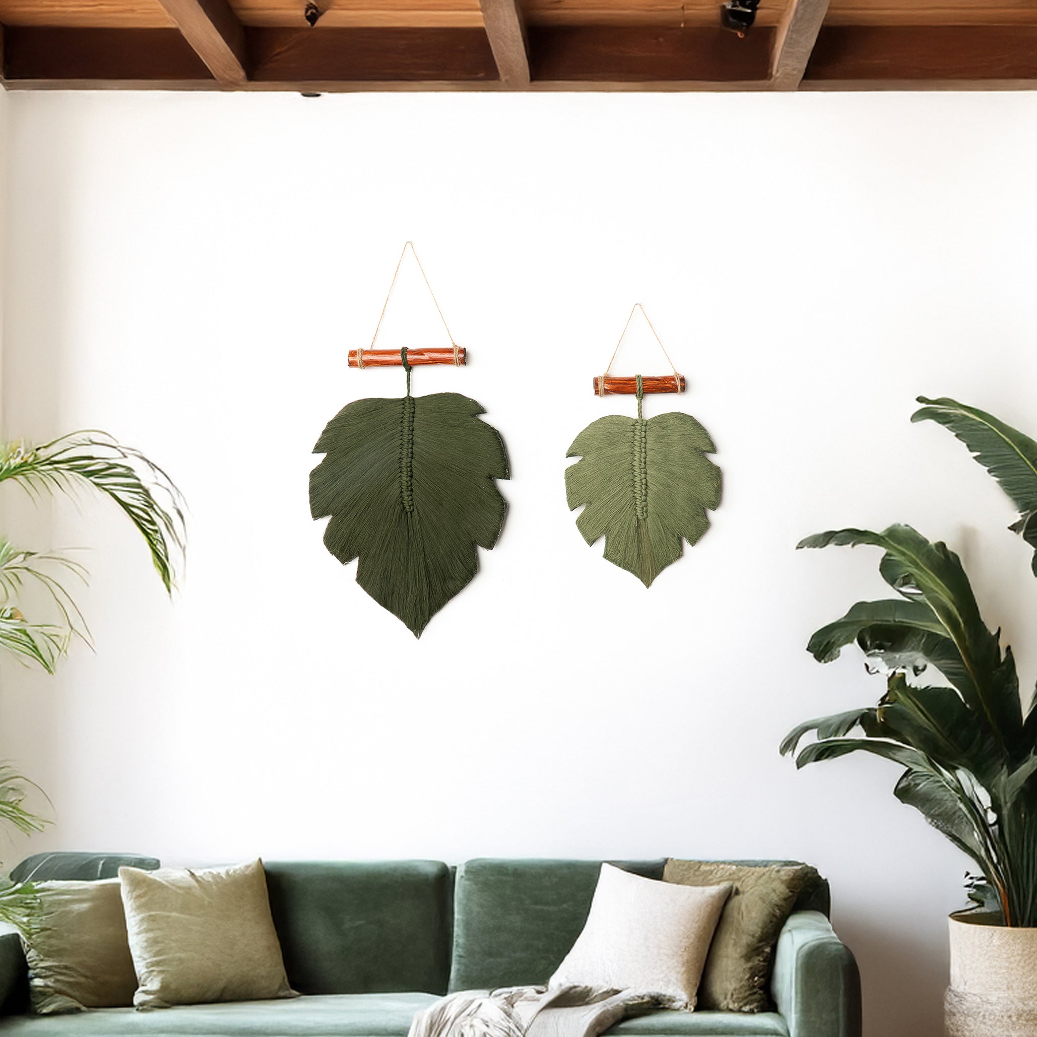 Two leaf-shaped wall hangings on a white wall above a green sofa with decorative pillows.