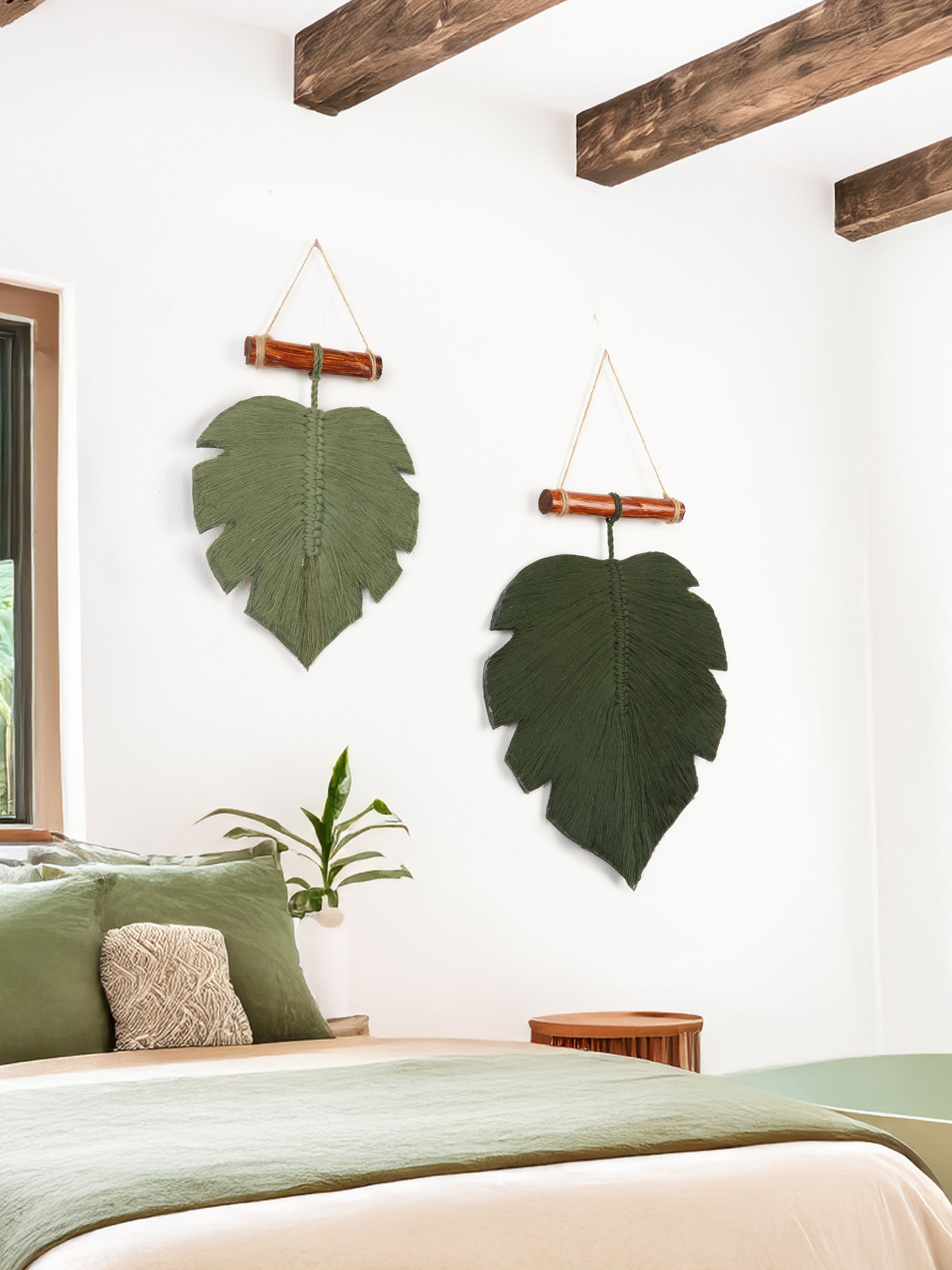 Decorative leaf wall hangings in a bedroom setting with a bed and pillows.