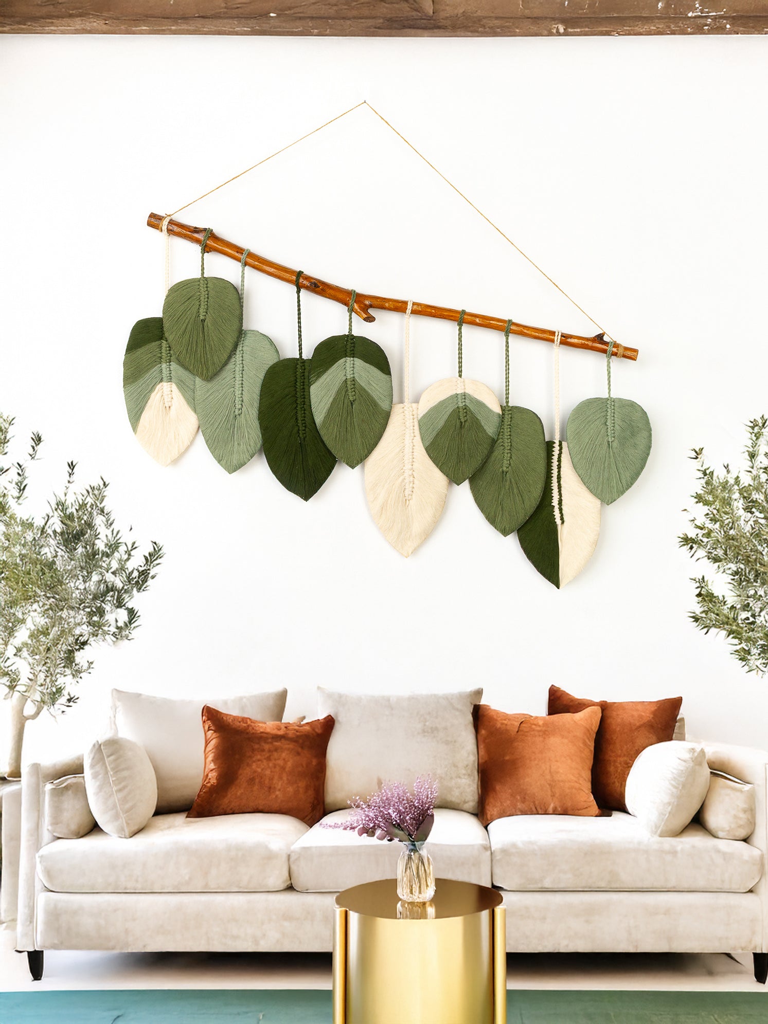 Decorative wall hanging with leaf-shaped elements above a sofa in a living room.