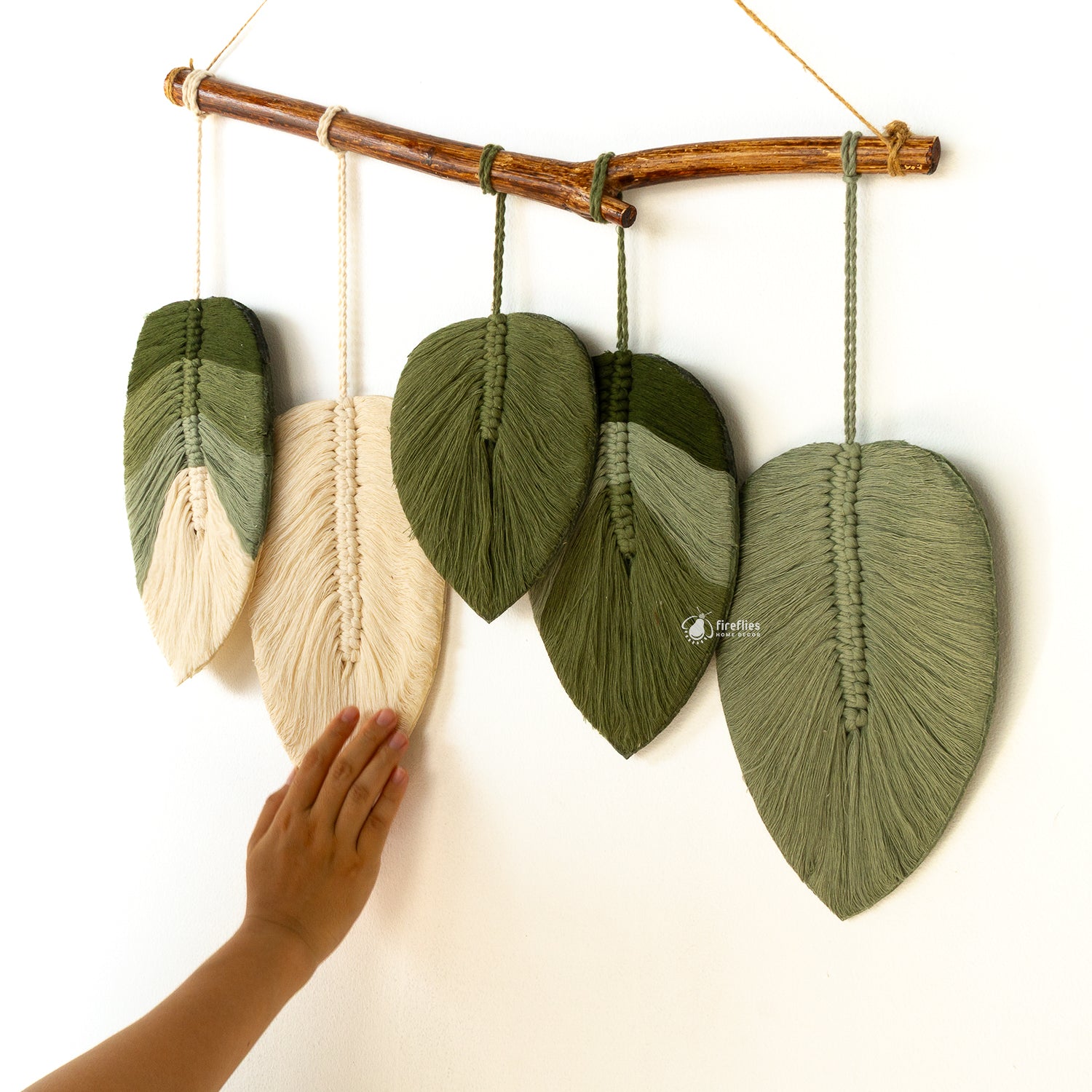 Macrame wall hanging with leaf-shaped green leaves on a white background