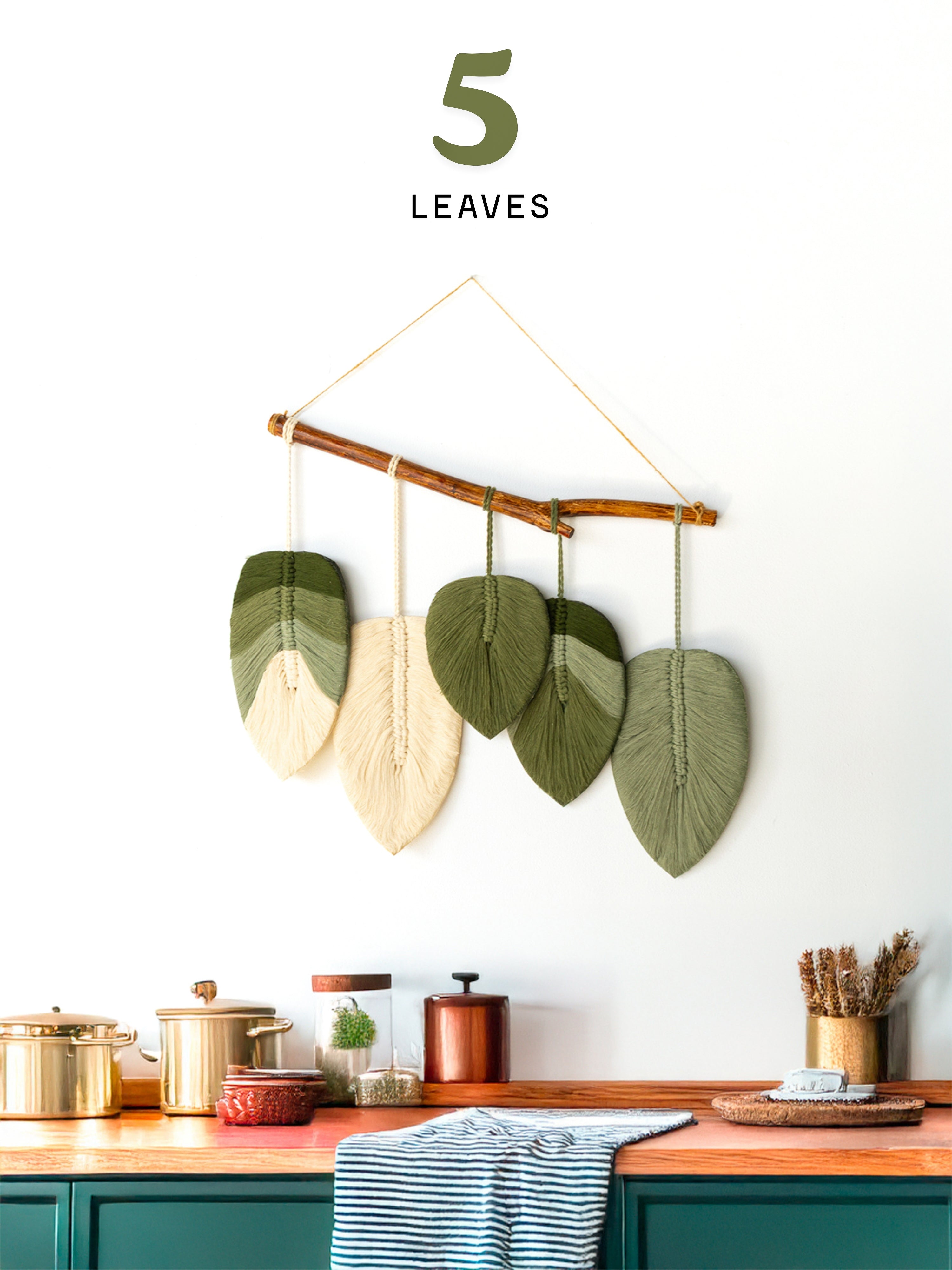 Decorative leaf wall art hanging above a kitchen counter with a neutral background.