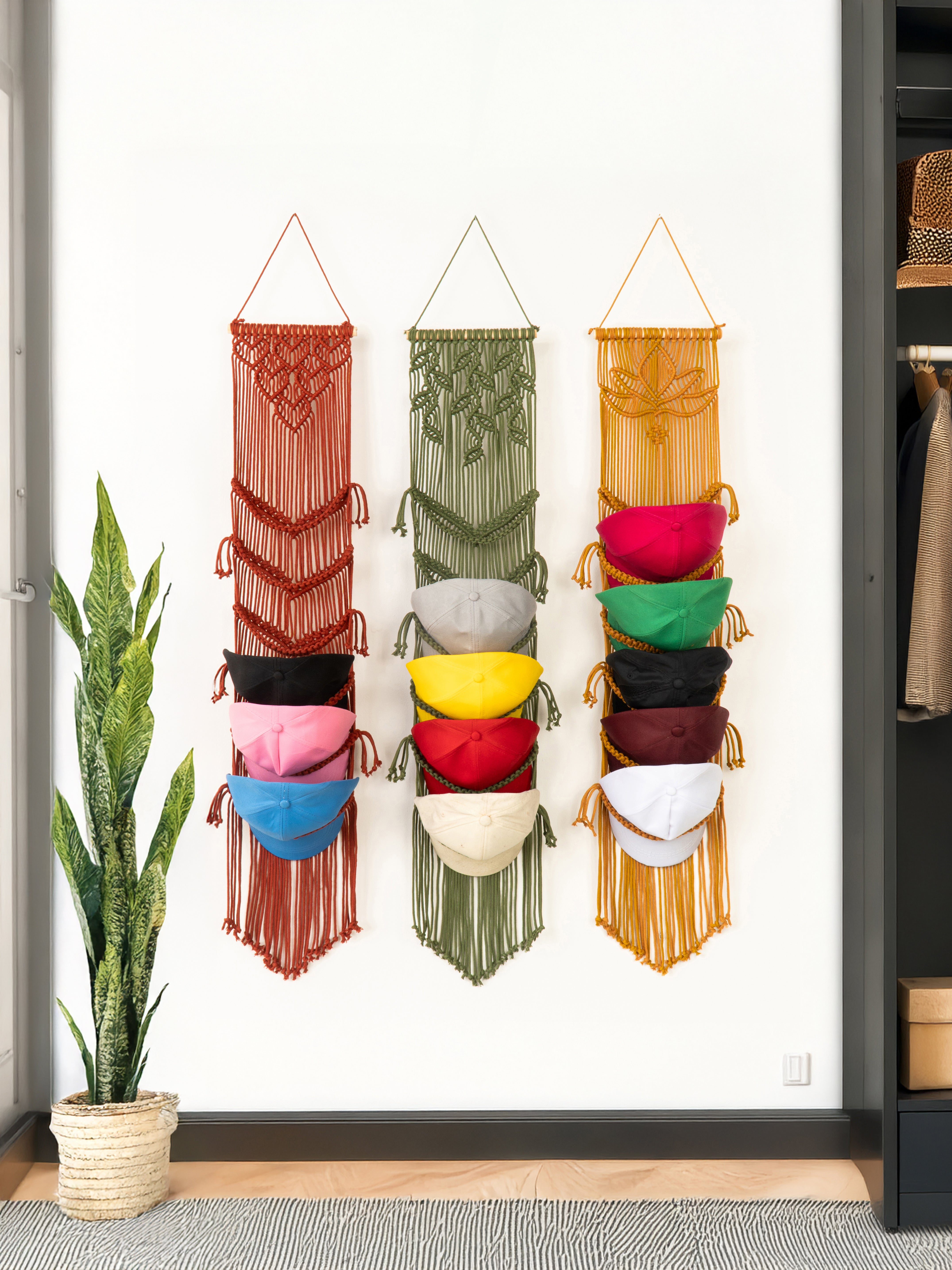 Colorful macrame wall hangings with hats on a white wall.