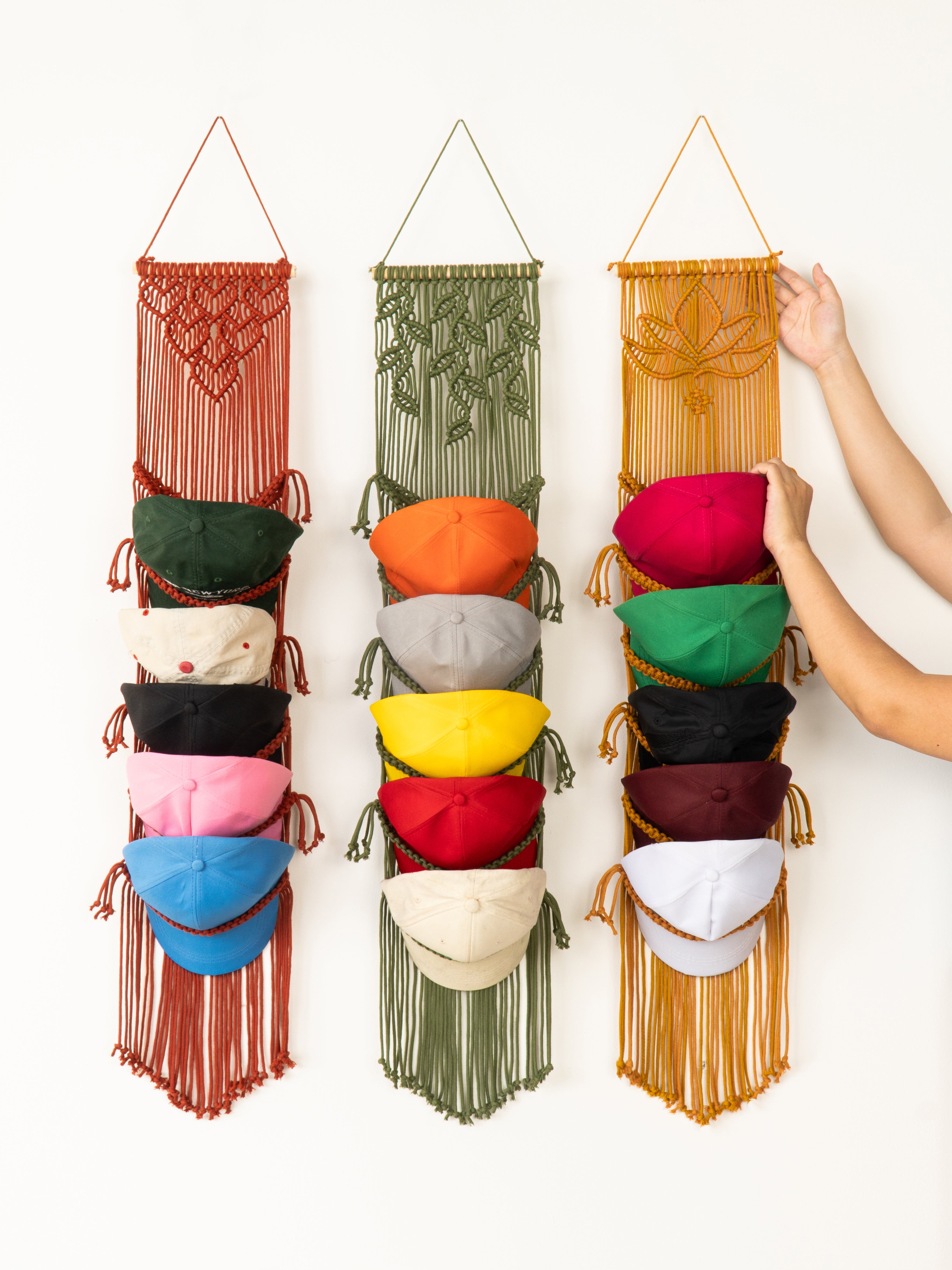 Three macrame wall hangings with colorful bowls on a white background