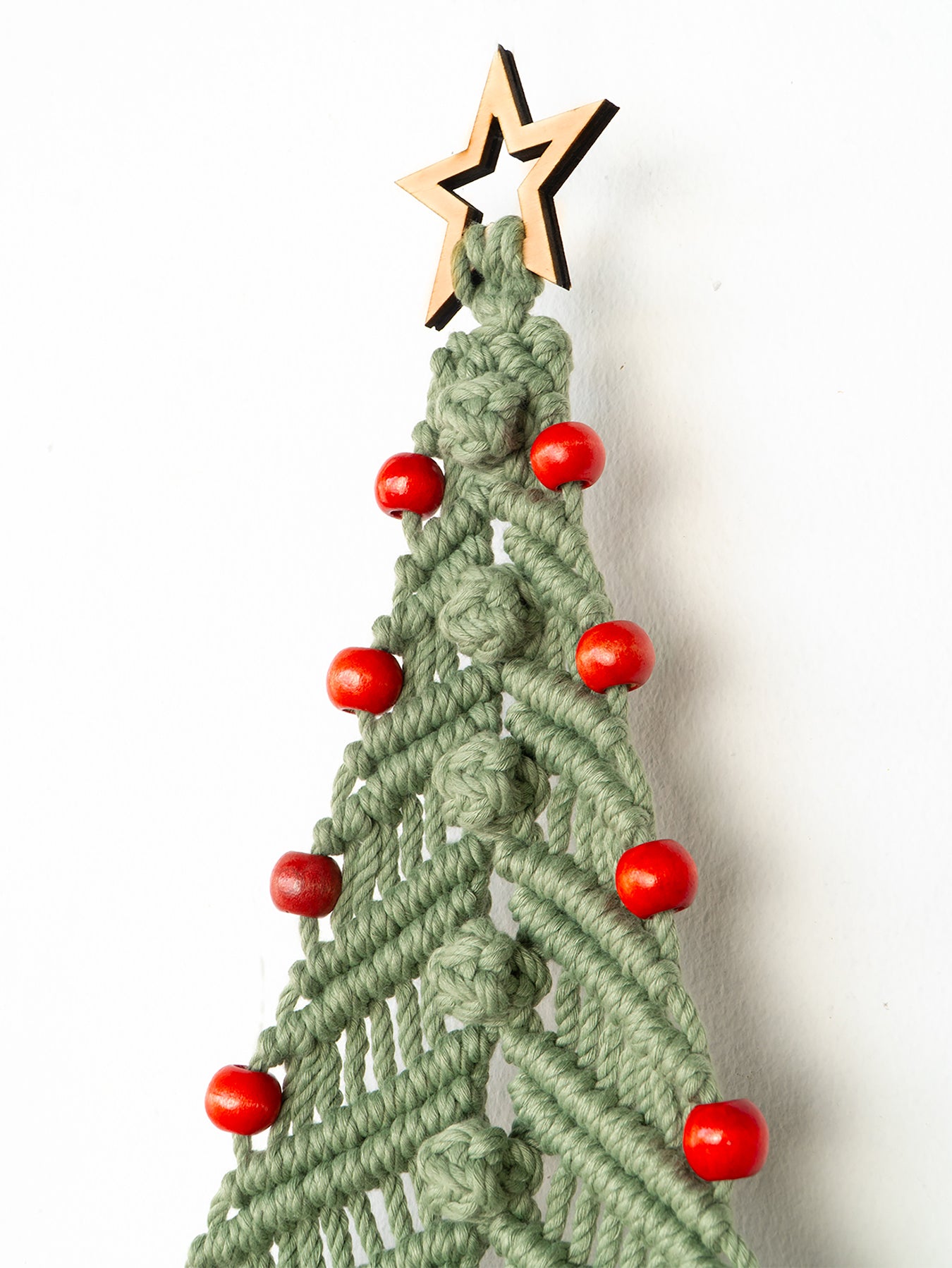 Macrame Christmas tree decoration with red beads and a wooden star on a white background