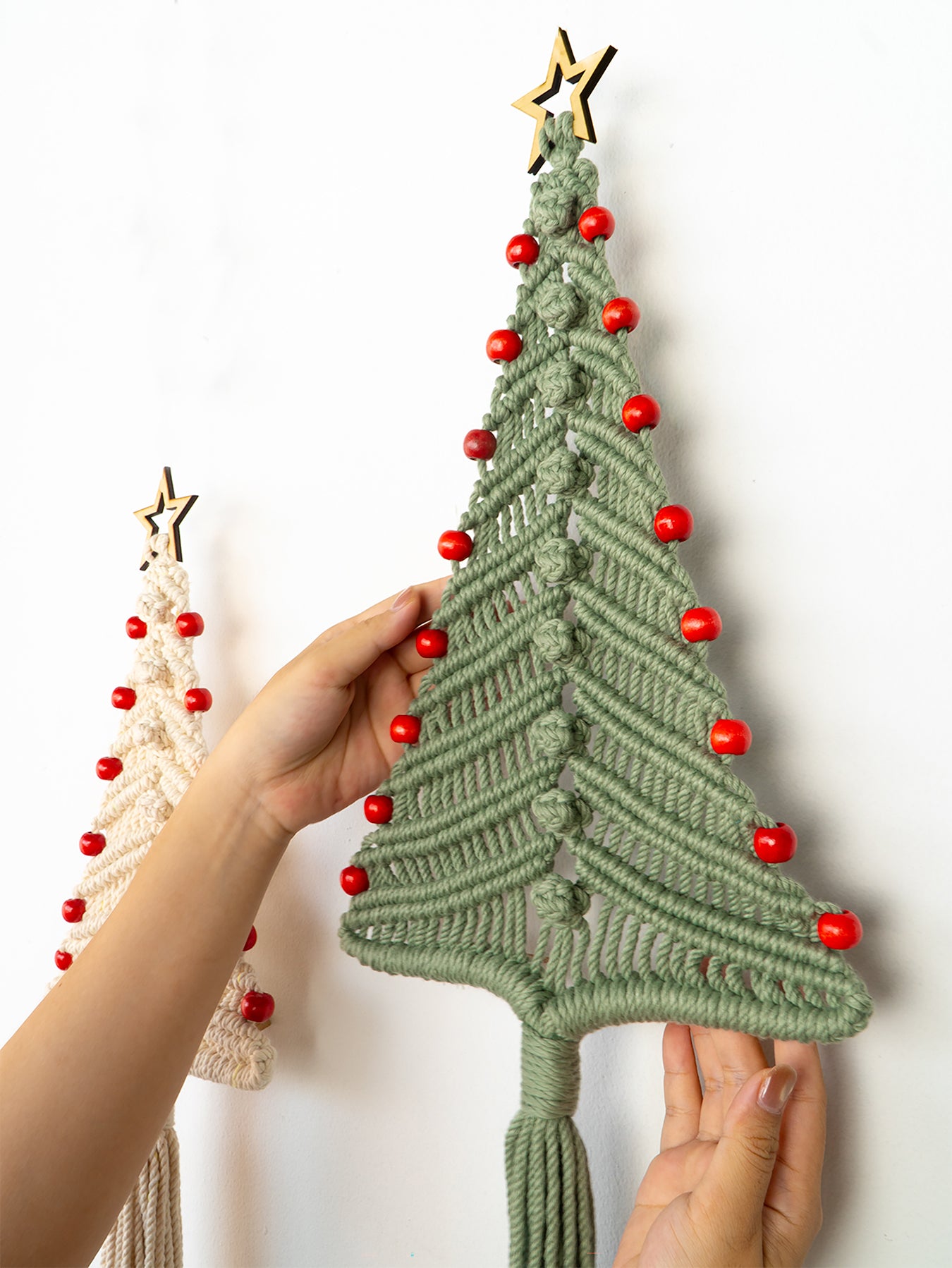 Handmade macrame Christmas tree with red beads and a gold star on a white background