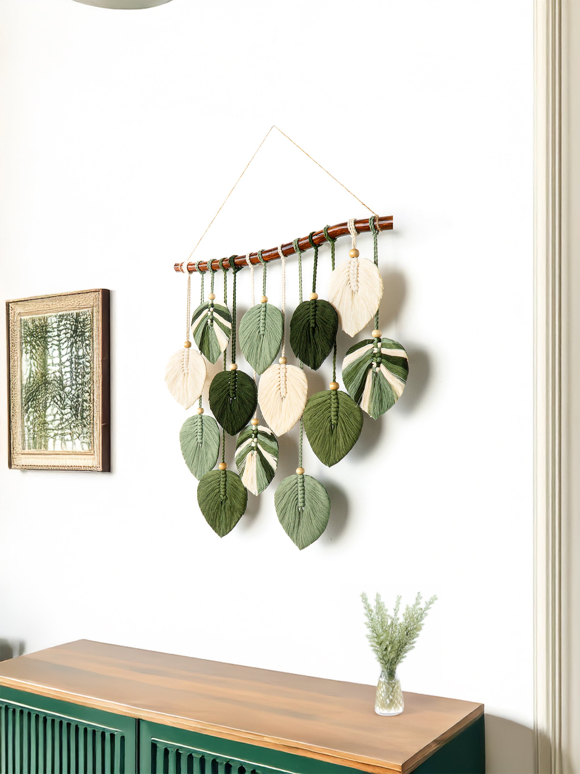 Decorative wall hanging with leaf-shaped ornaments on a white wall.