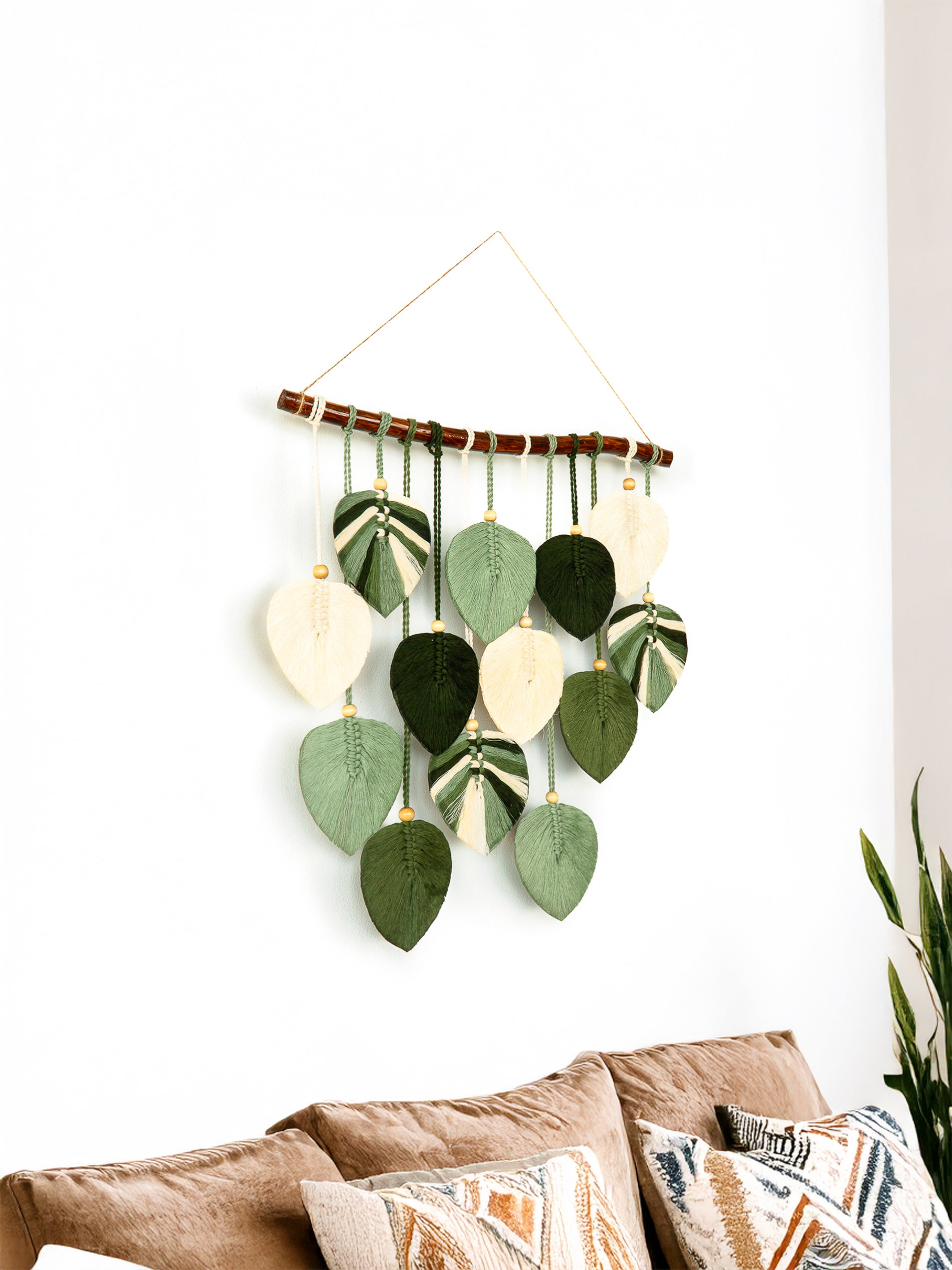 Decorative wall hanging with leaf-shaped elements on a white wall.