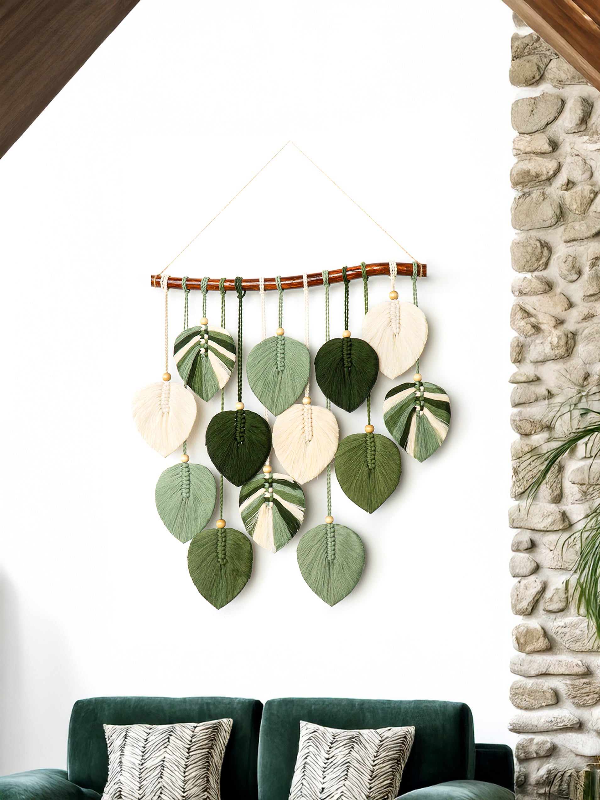 Decorative wall hanging with leaf-shaped ornaments on a white wall next to a stone fireplace.
