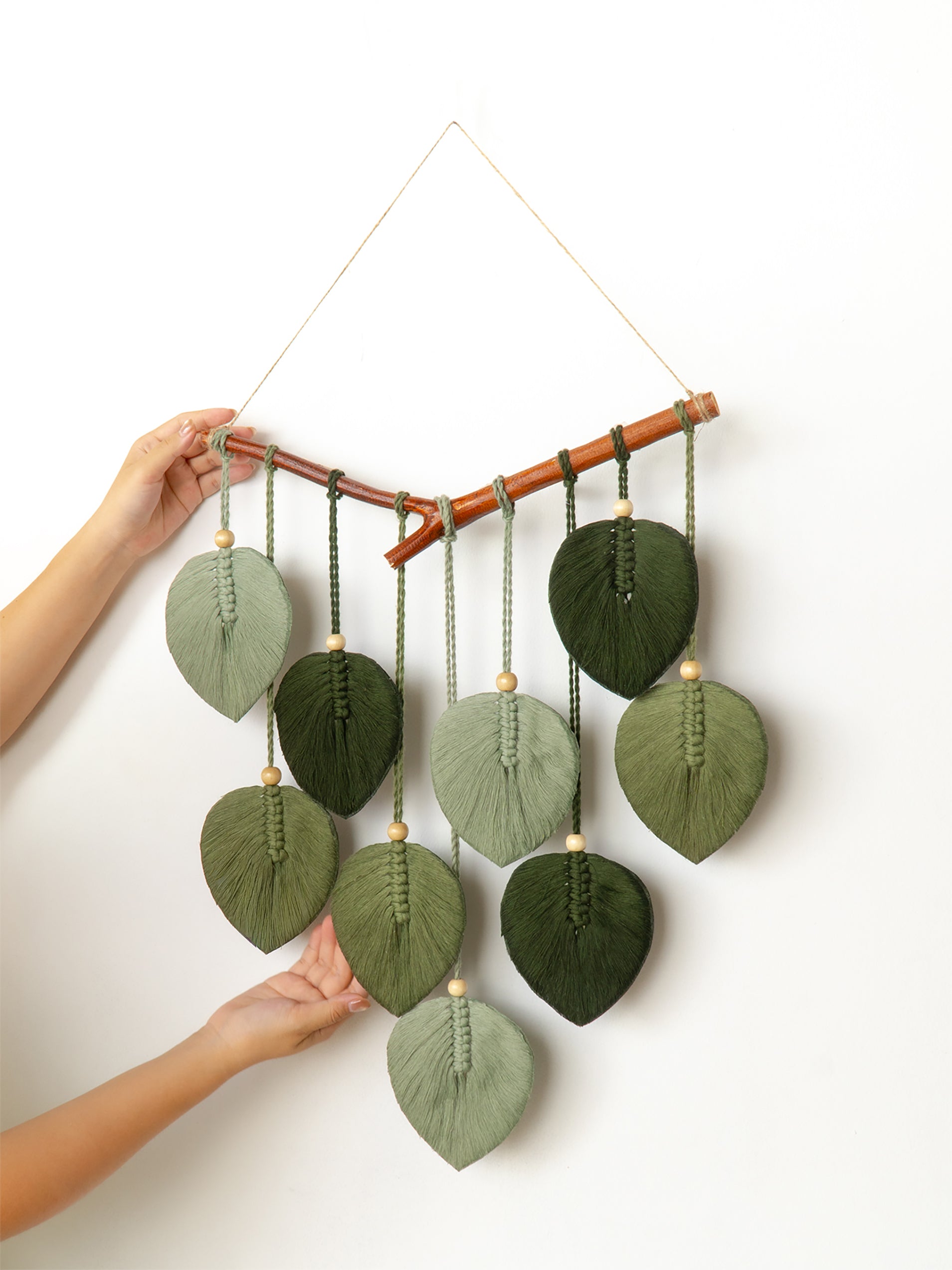 Pastel-colored leaf-shaped wall hanging with beads on a white background