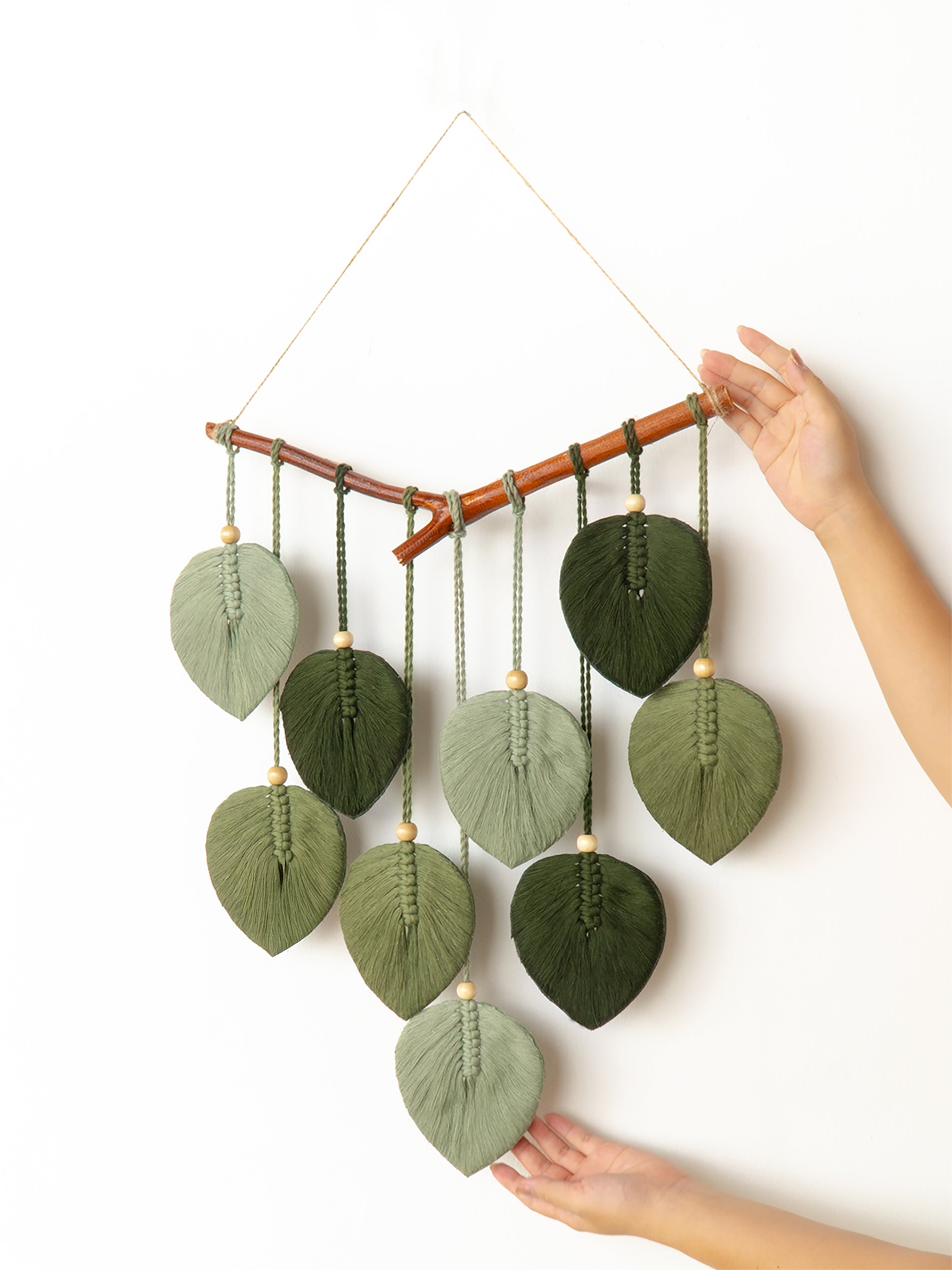 Colorful knitted leaf-shaped mobile hanging on a white background
