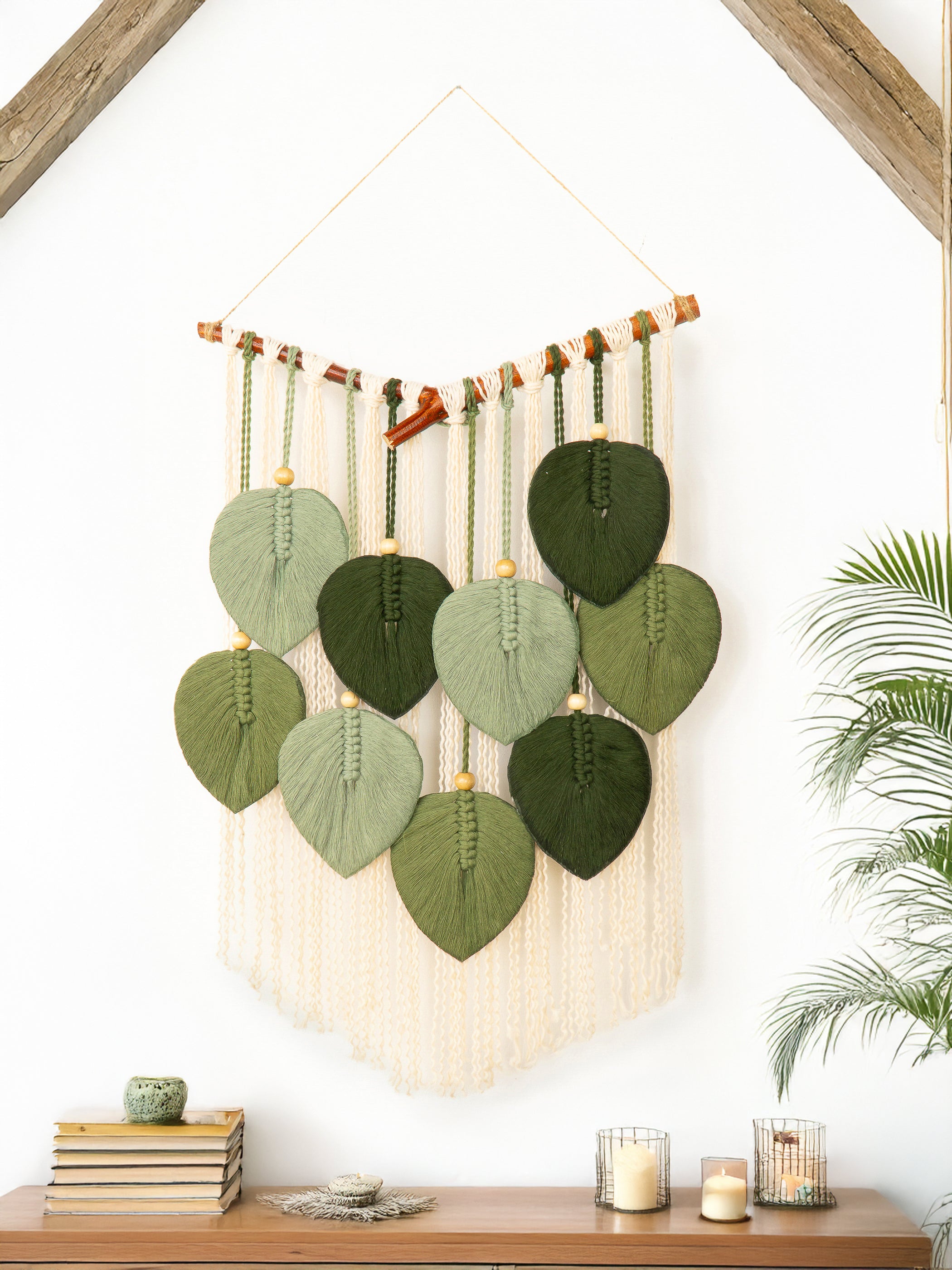 Decorative wall hanging with green leaf-shaped elements on a white wall.