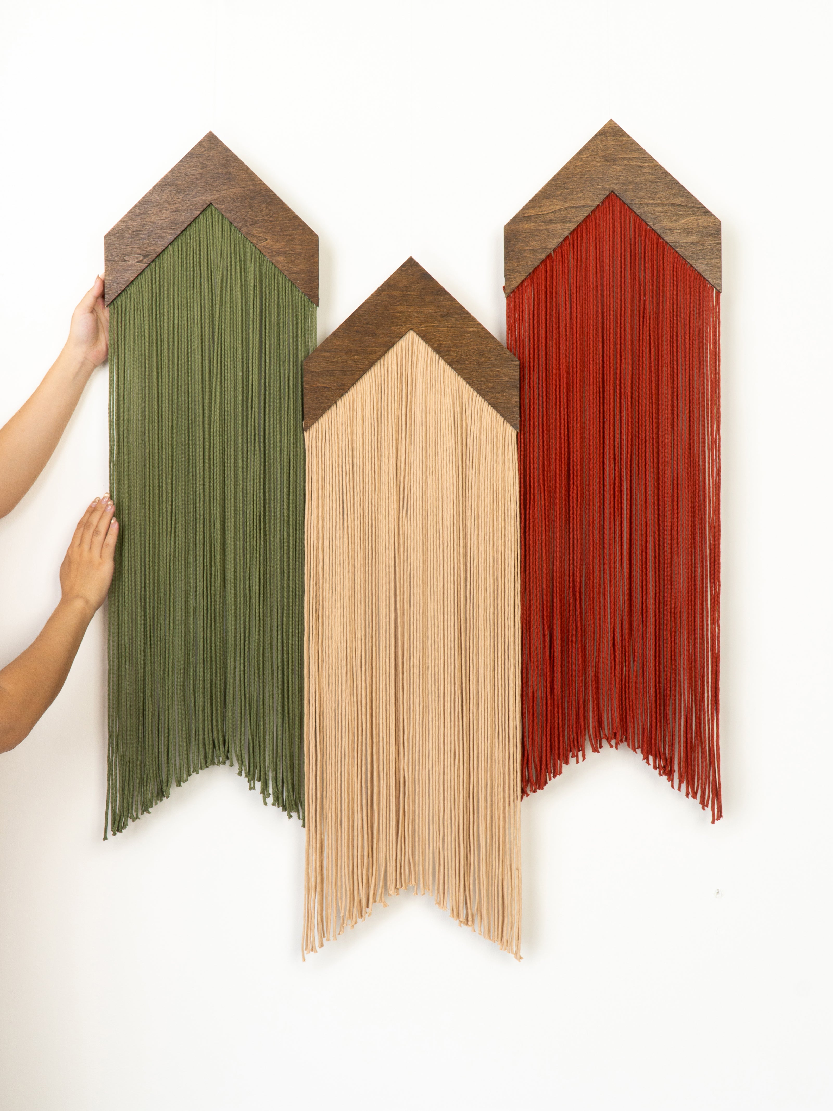 Three wooden wall art pieces in green, beige, and red on a white background.