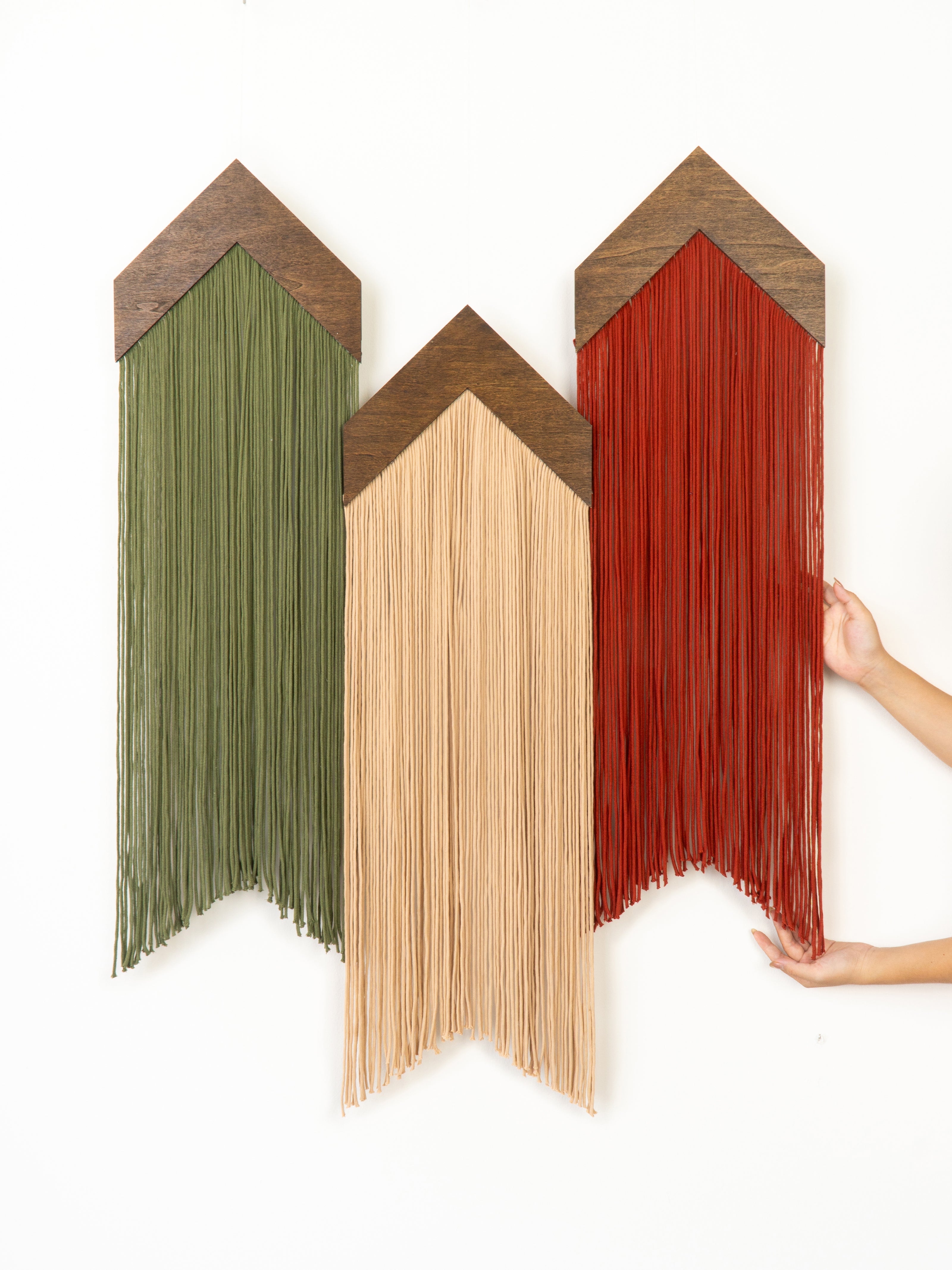 Three wooden wall art pieces in green, beige, and red on a white background.