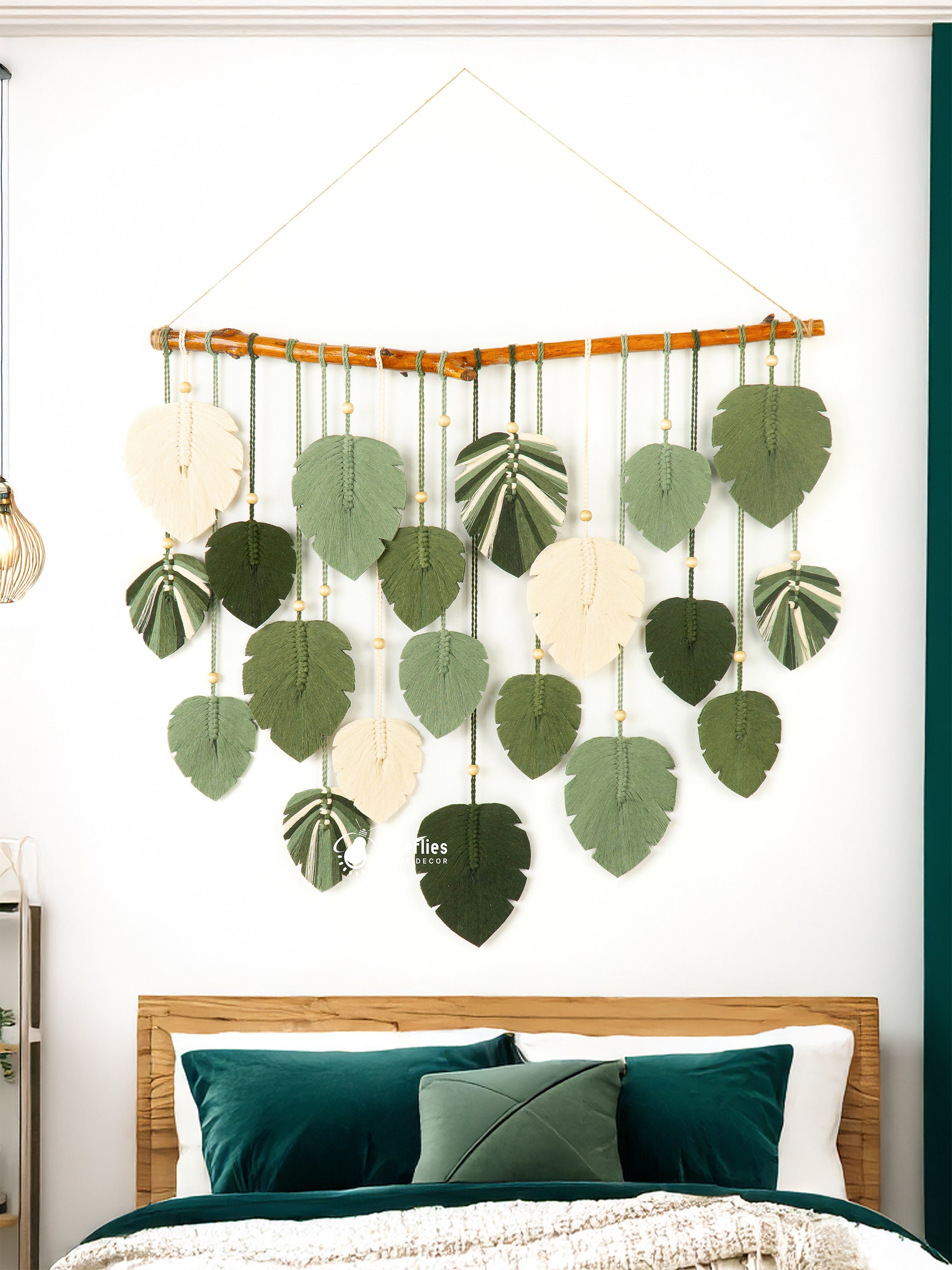 Decorative wall hanging with leaf patterns above a bed with green bedding.