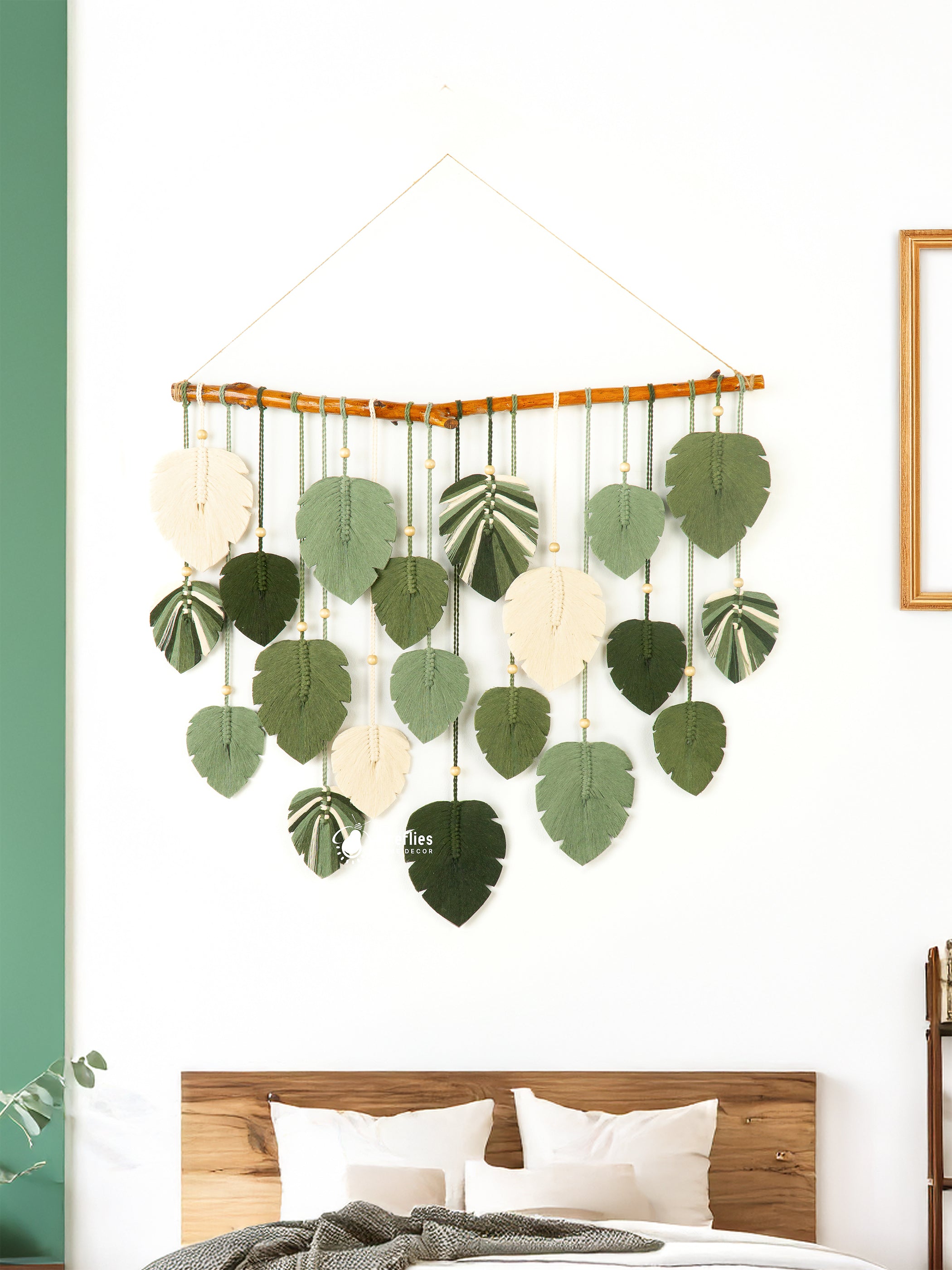 Decorative wall hanging with leaf patterns above a bed in a room with green walls.