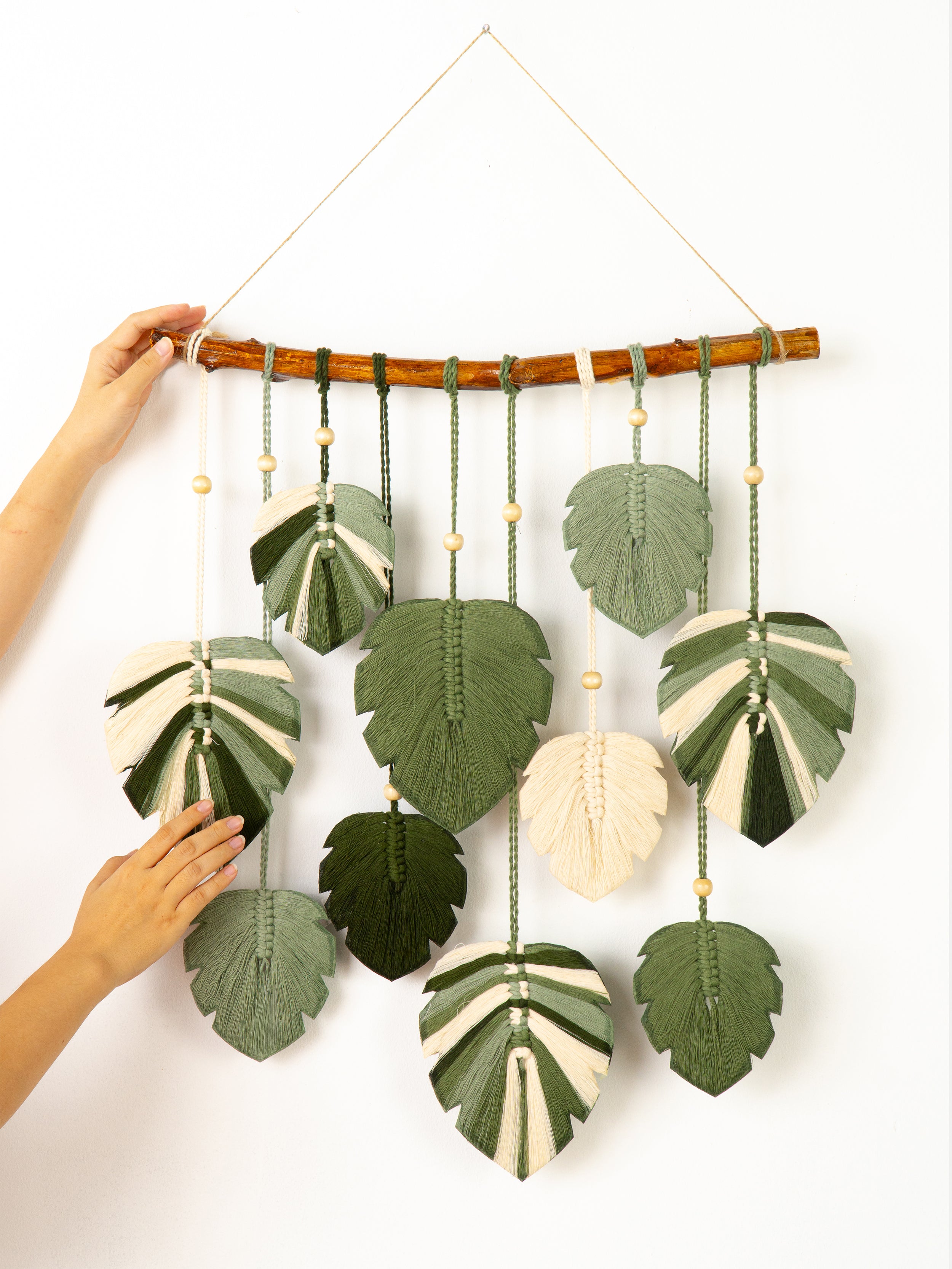 Handmade wall hanging with leaf-shaped green and white fabric pieces on a white background