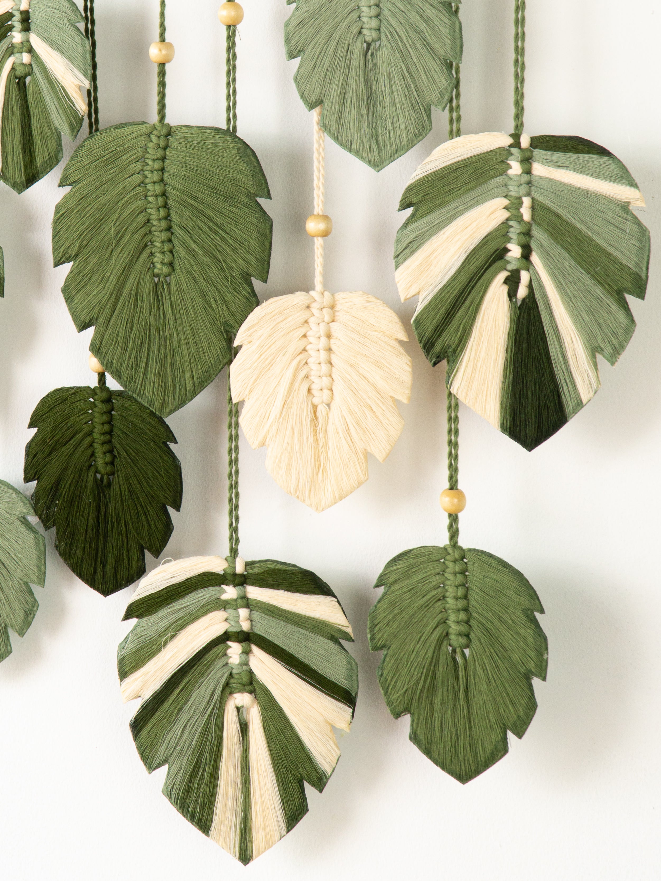 Decorative wall hanging with leaf-shaped macramé elements on a white background
