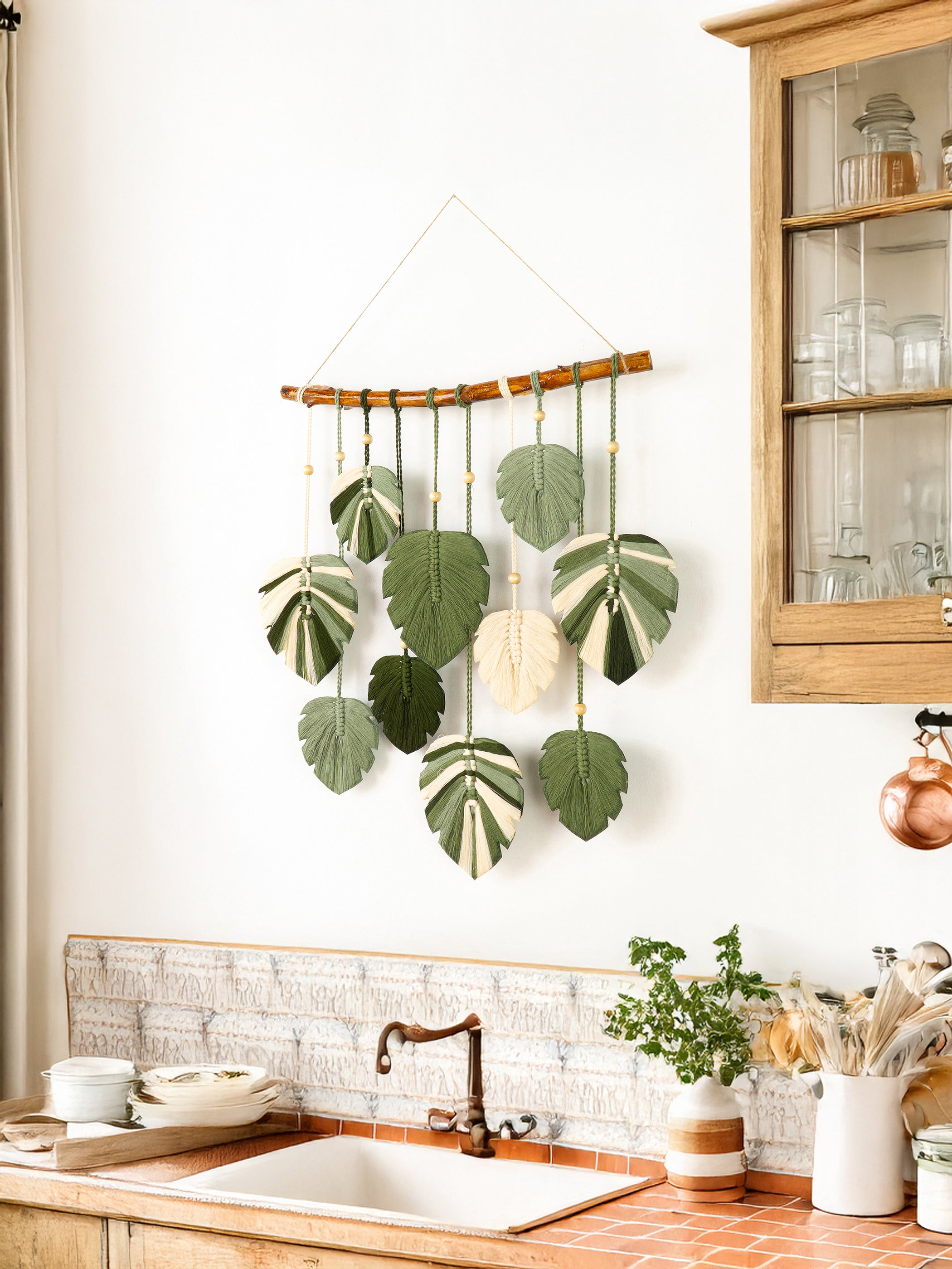 Decorative wall hanging with leaf patterns above a kitchen sink.