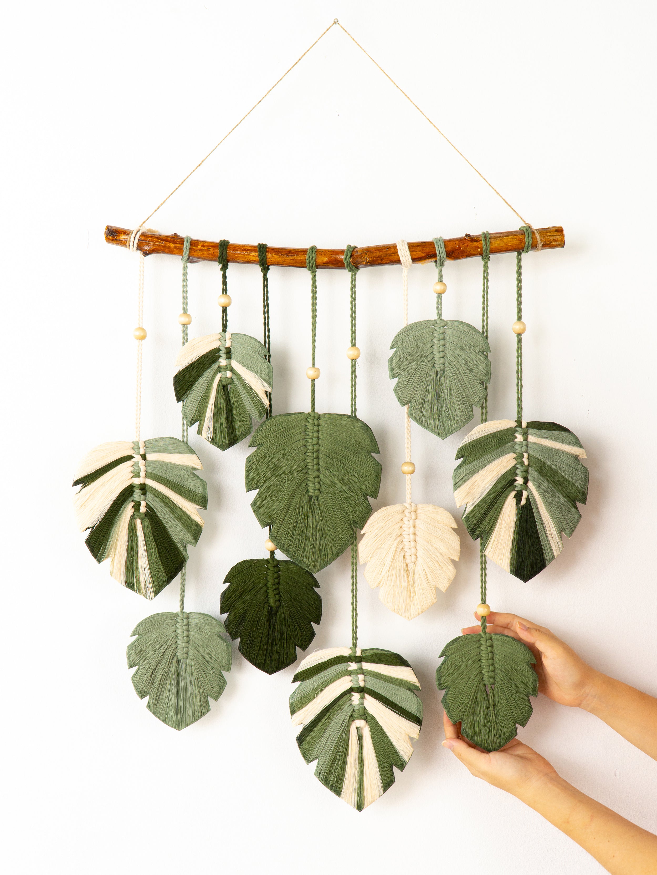 Handmade wall hanging with leaf-shaped green and white fabric pieces on a white background
