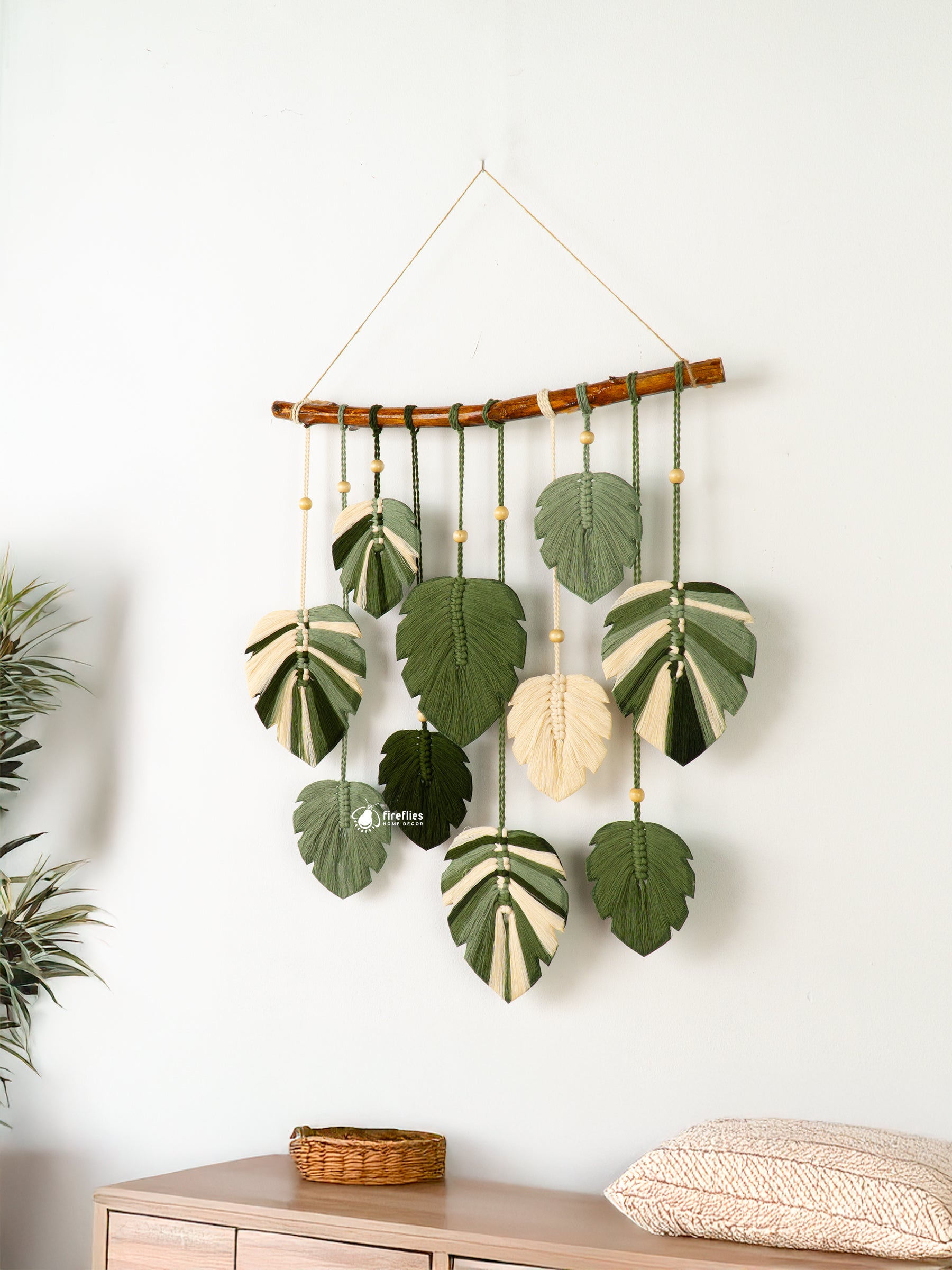 Decorative wall hanging with leaf patterns on a white wall.