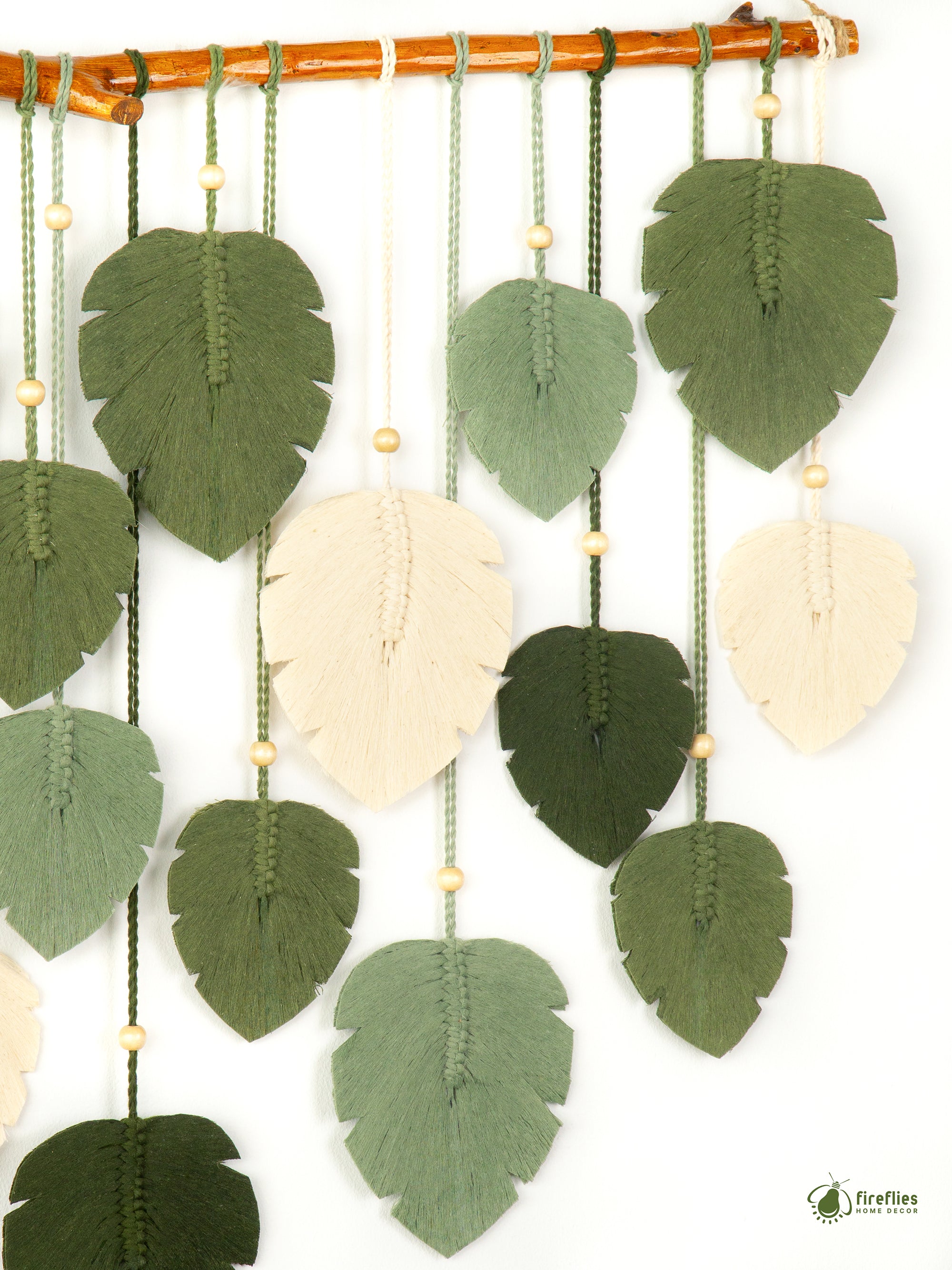 Decorative hanging with green and beige leaf-shaped pieces on a white background
