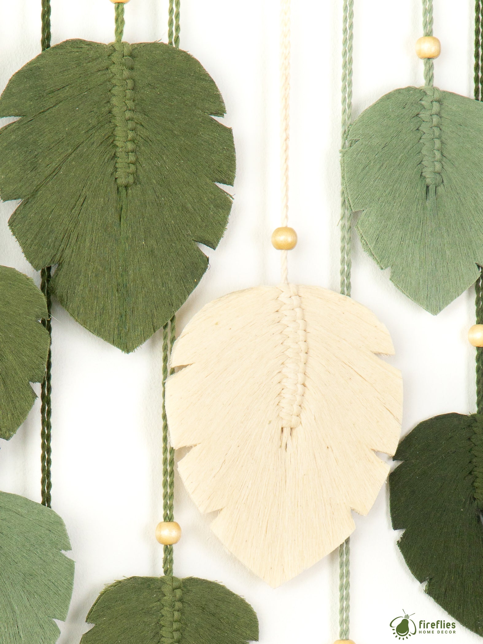 Decorative wall hanging with leaf-shaped fabric pieces and beads on a white background