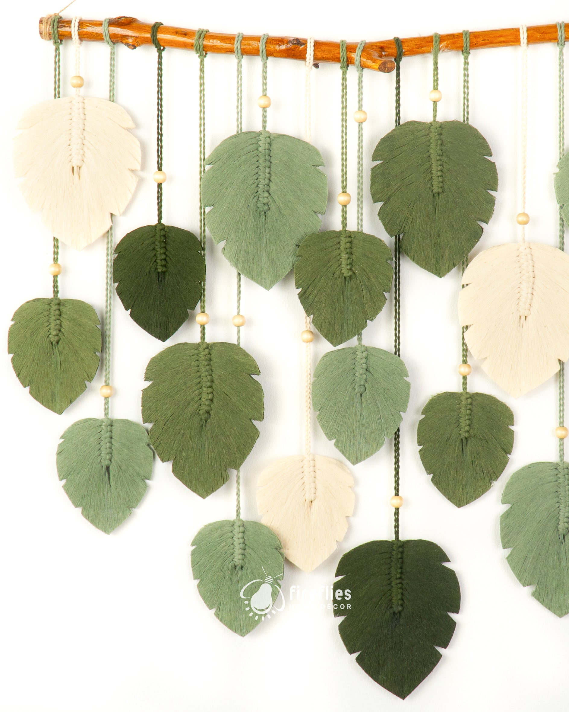 Decorative wall hanging with green leaf-shaped felt pieces and white circles on a white background.