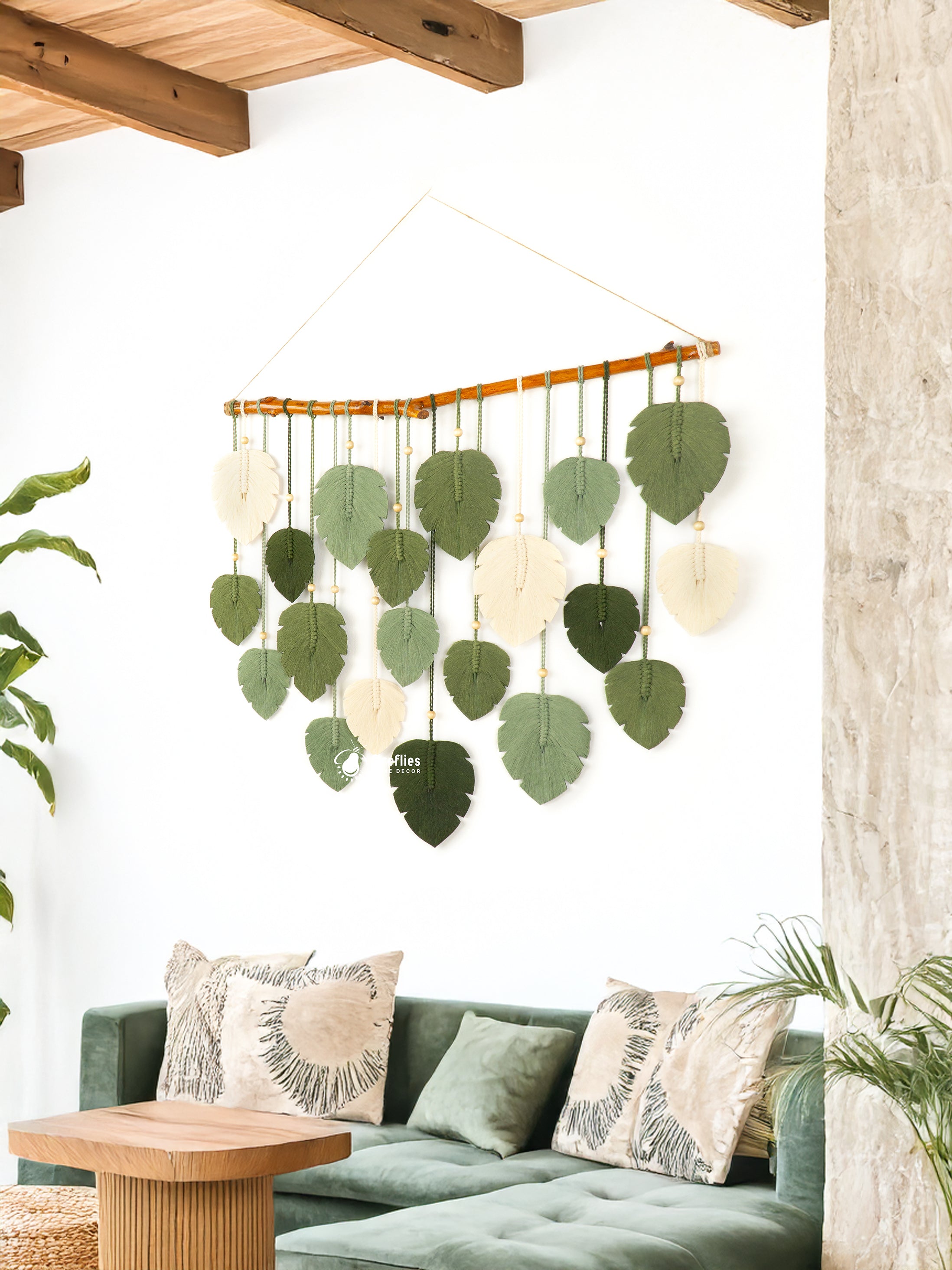Decorative wall hanging with green leaves and white circles above a living room with a green sofa.
