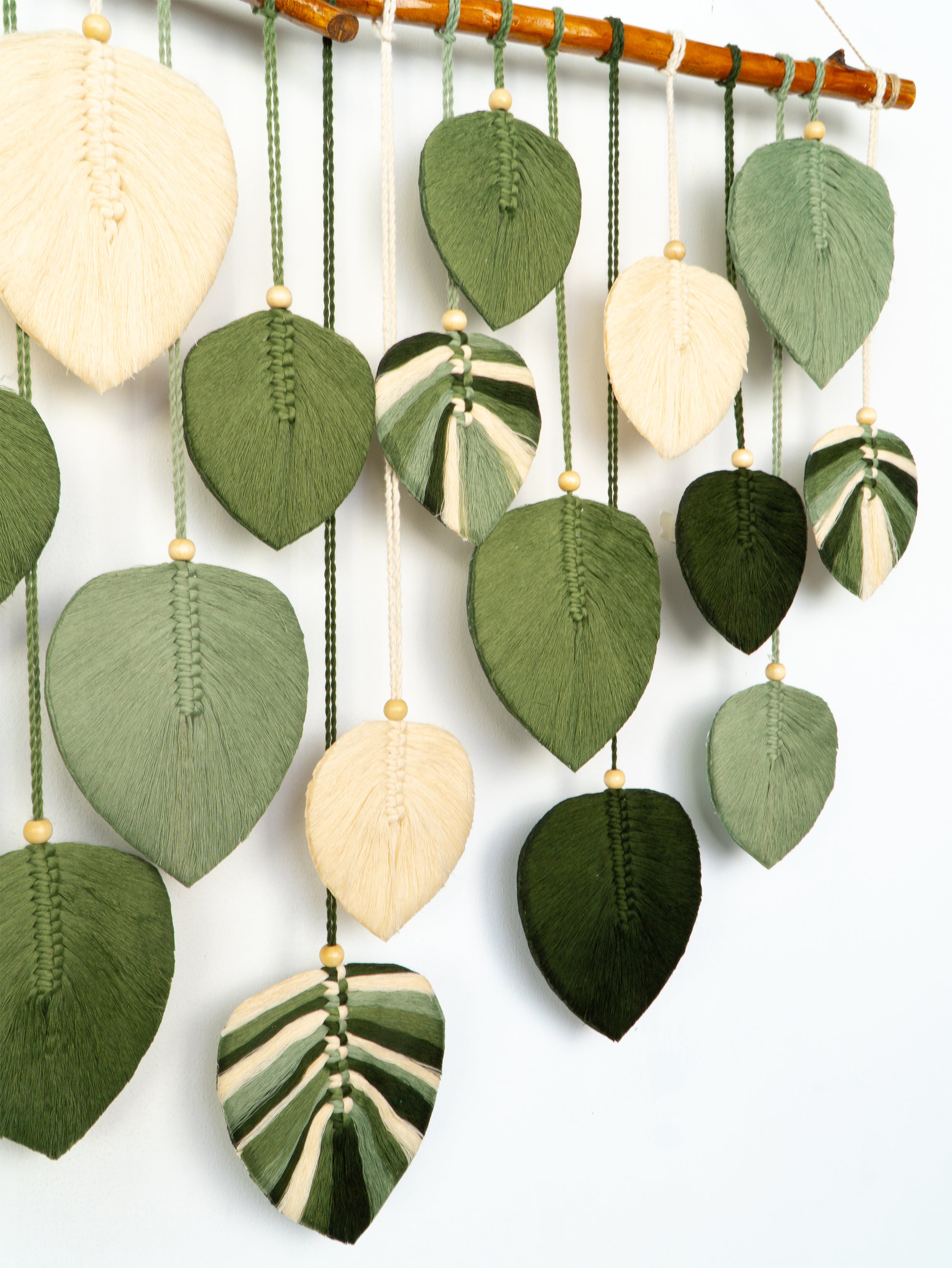 Decorative wall hanging with leaf-shaped ceramic pieces on a white background