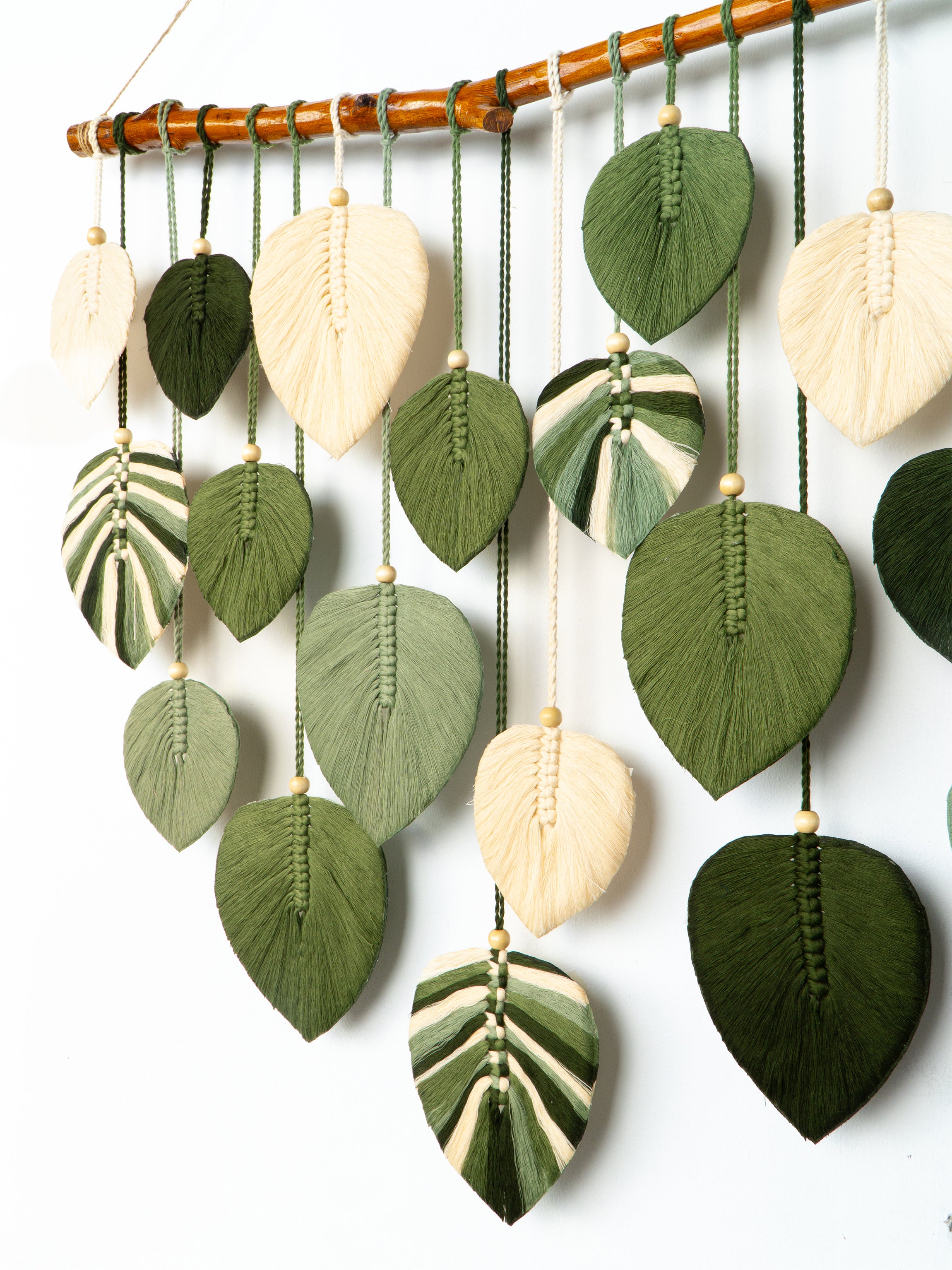 Decorative wall hanging with leaf-shaped ceramic pieces on a white background