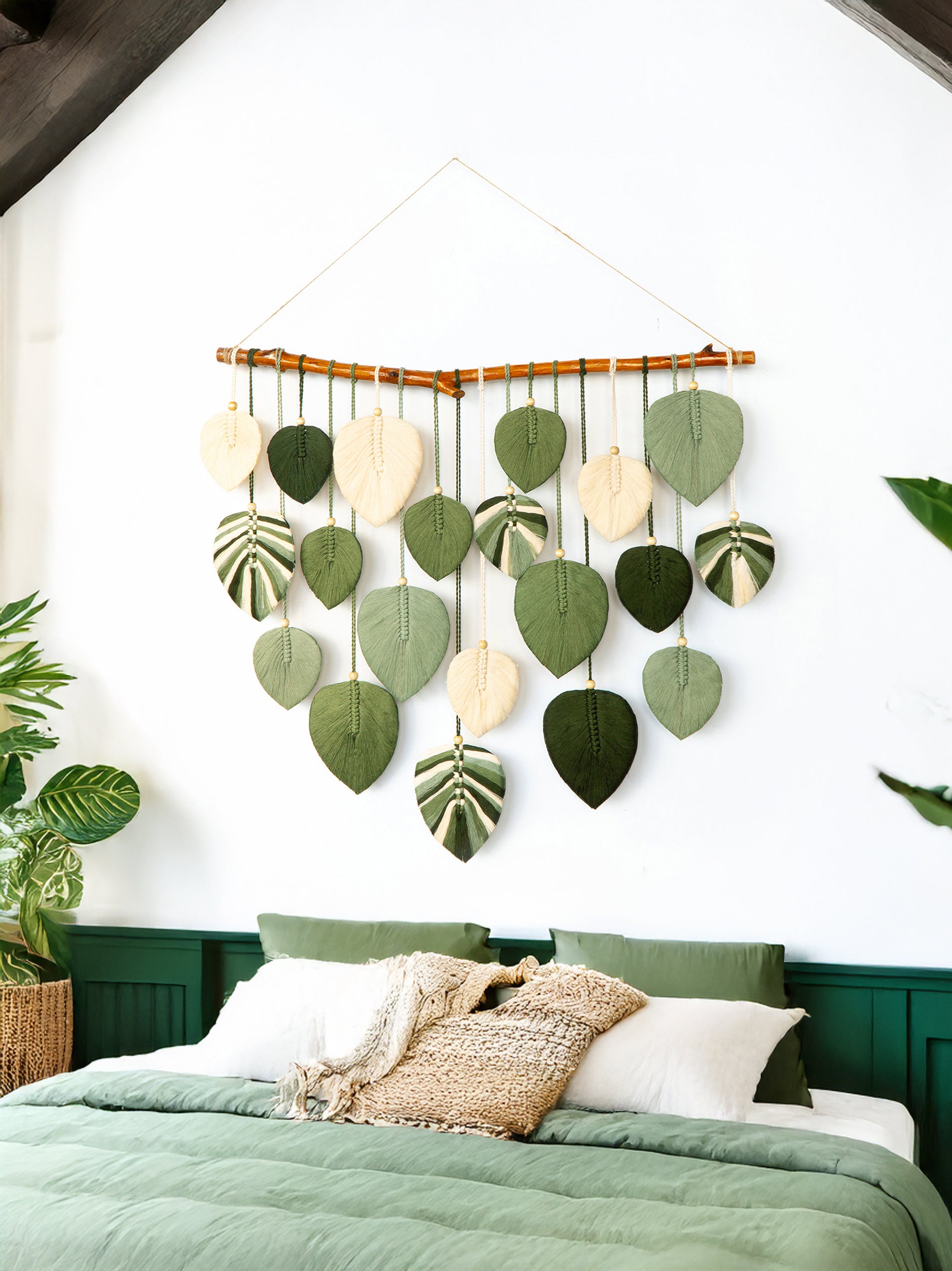 Decorative wall hanging with leaf shapes above a bed in a bedroom setting.