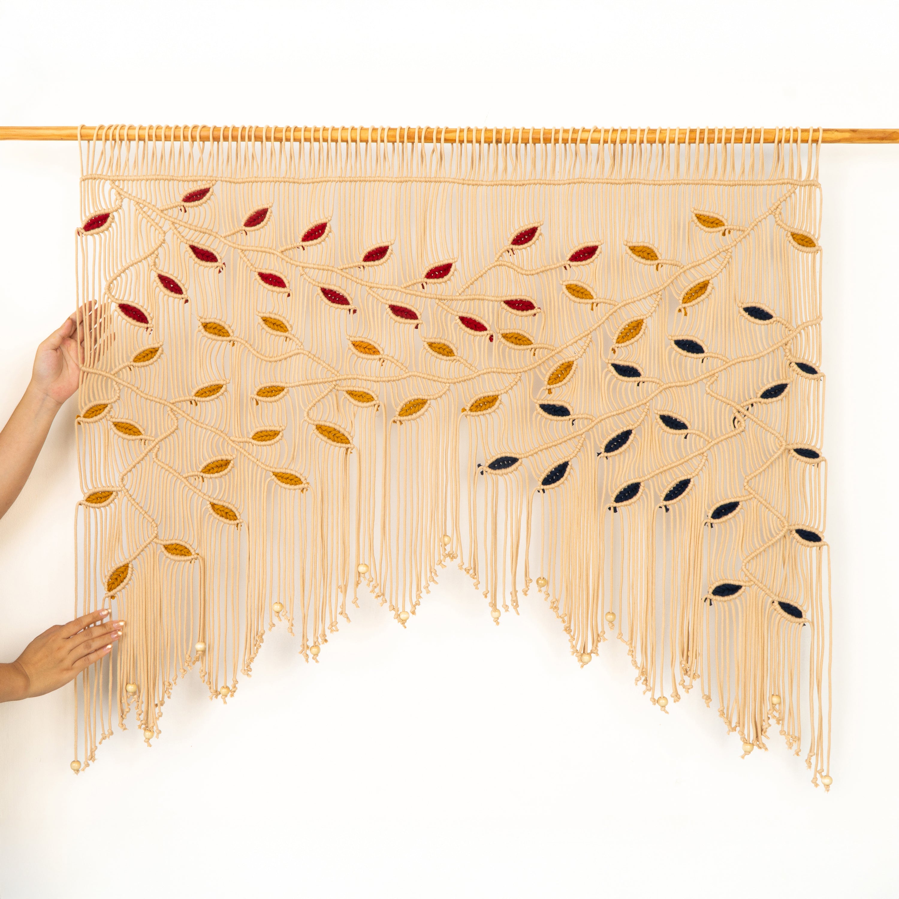 Handmade wall art with woven design and colored beads on a white background