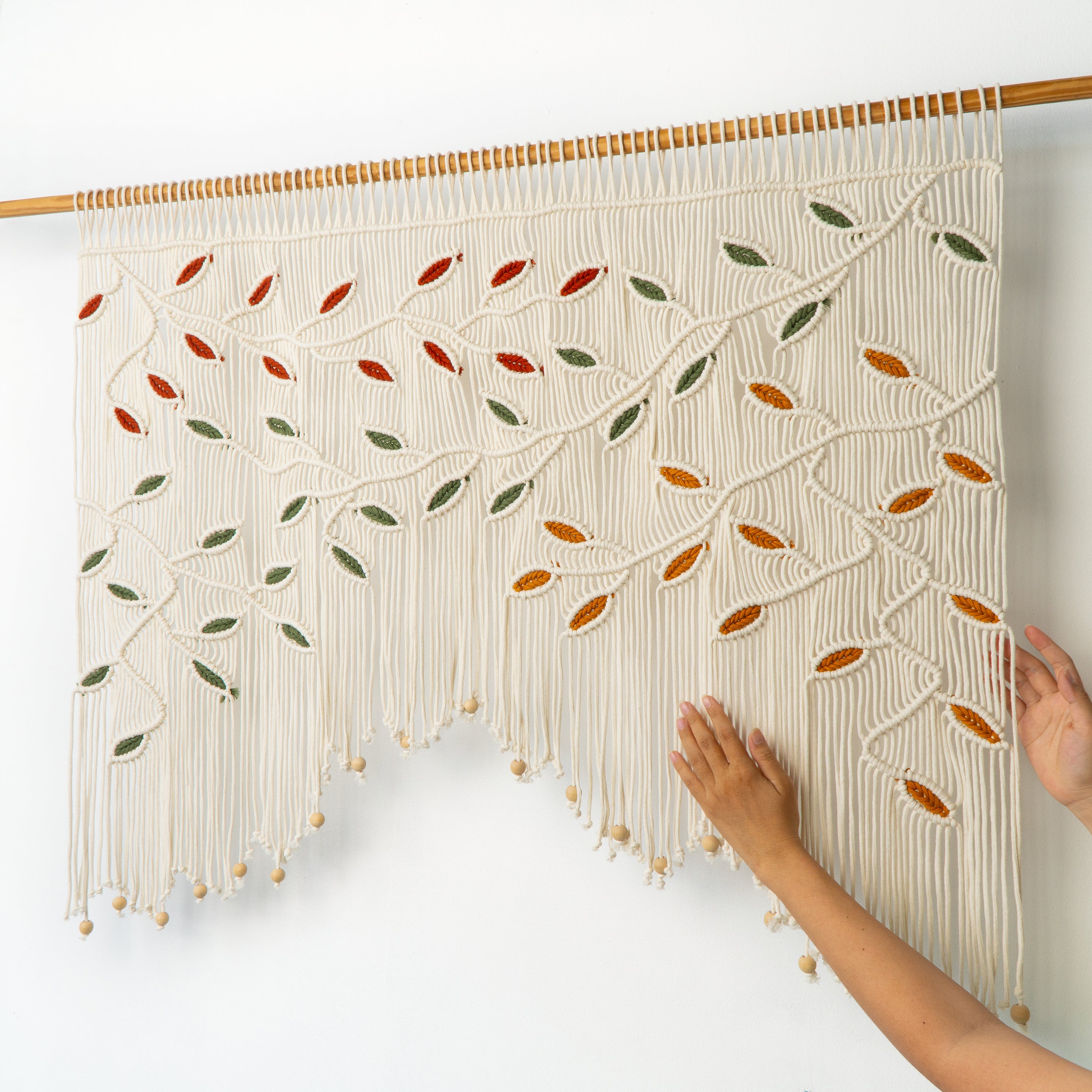 Macrame wall hanging with leaf patterns on a white background