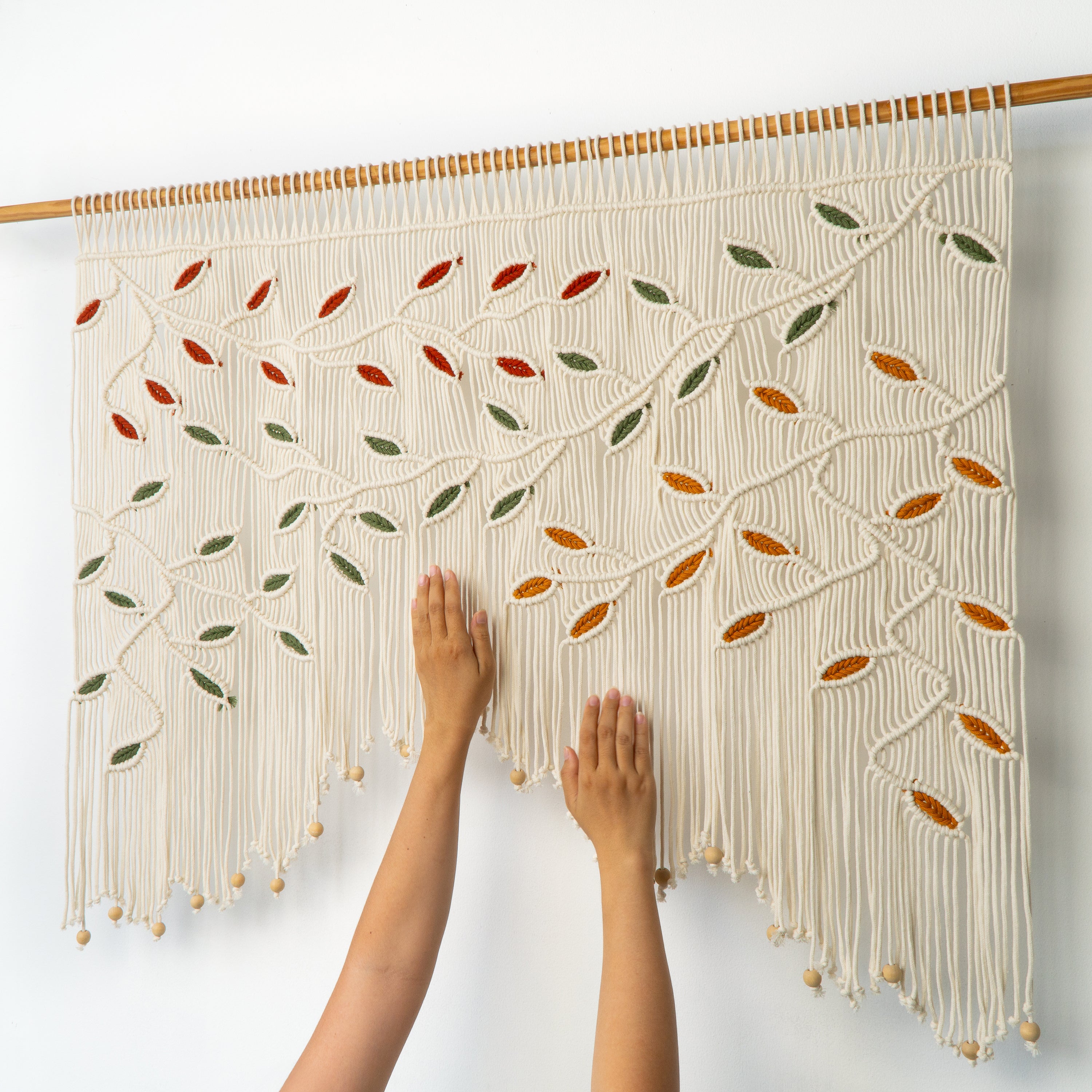 Macrame wall hanging with leaf patterns on a white background