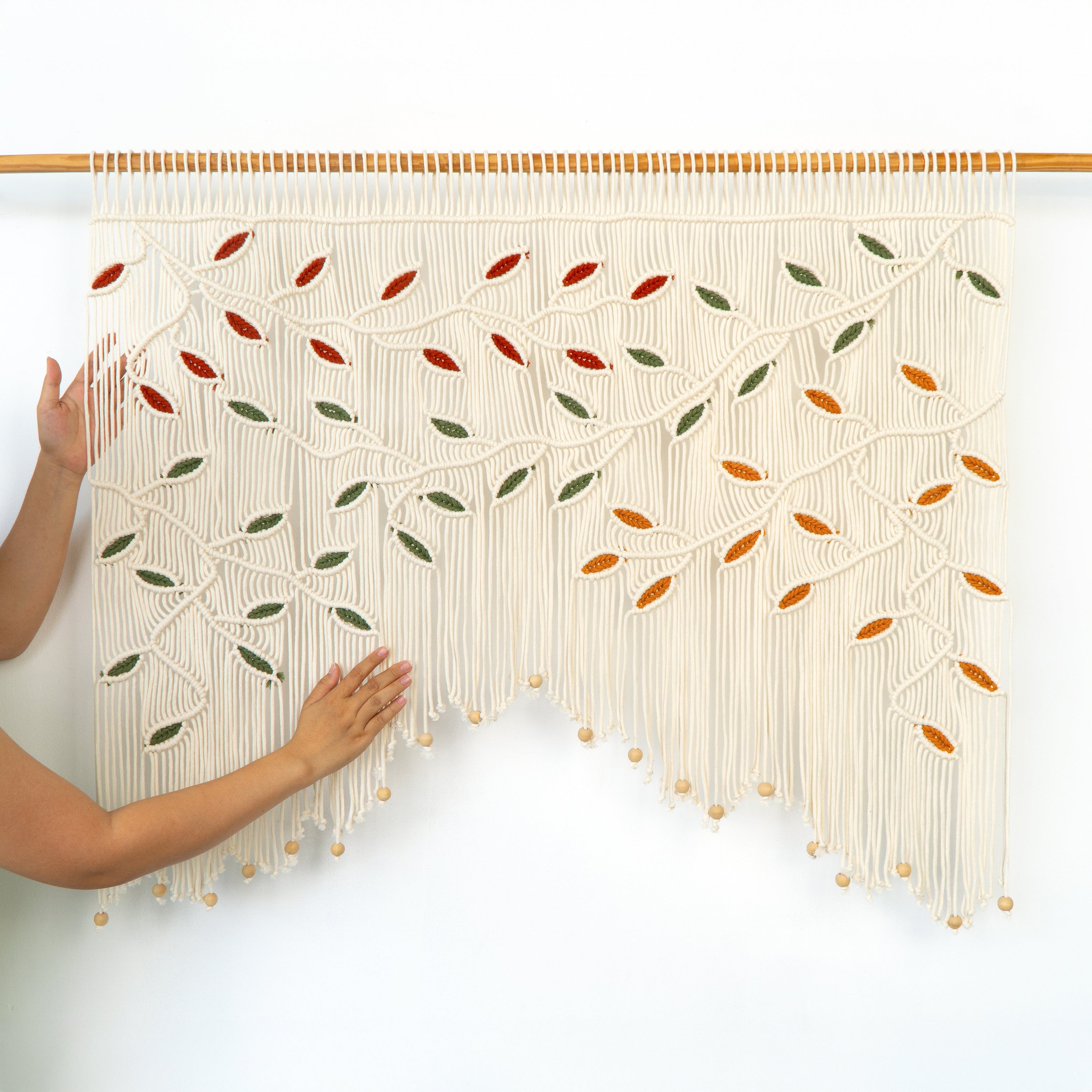 Handmade woven wall art with leaf patterns on a white background