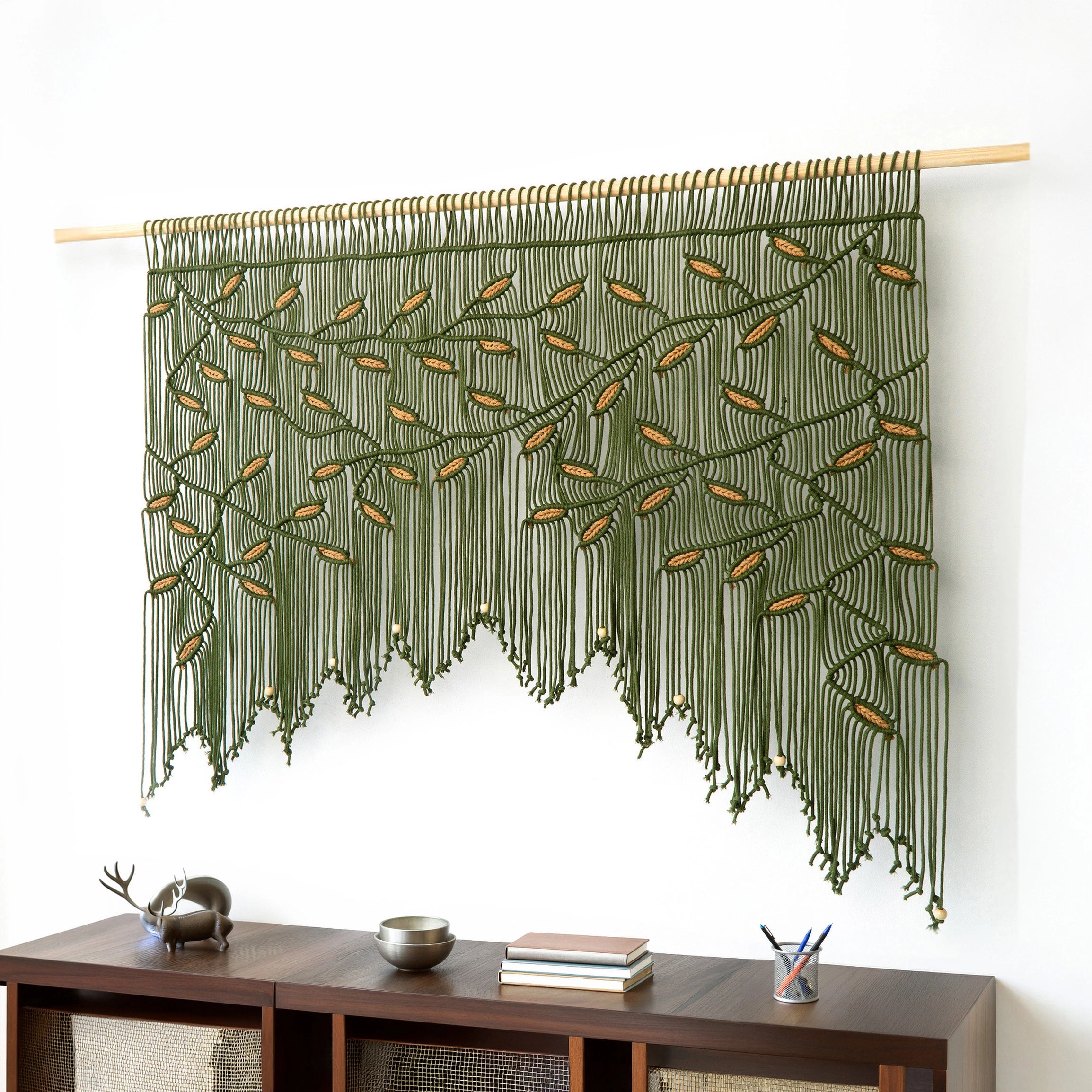 Wide horizontal fiber art in forest green cord featuring earthy terracotta leaf highlights and wood beads.