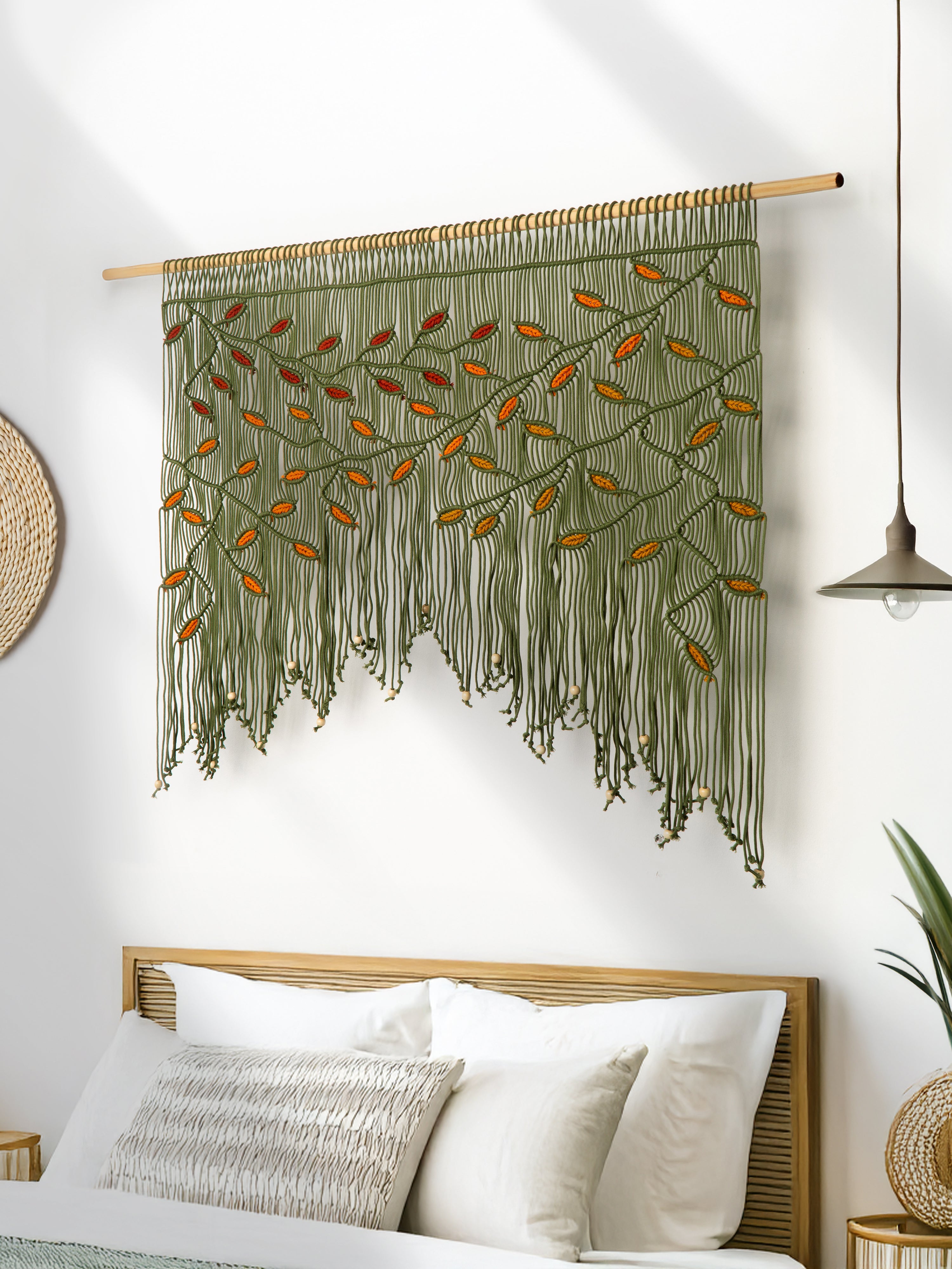 Decorative wall hanging with leaf patterns on a white wall above a sofa.