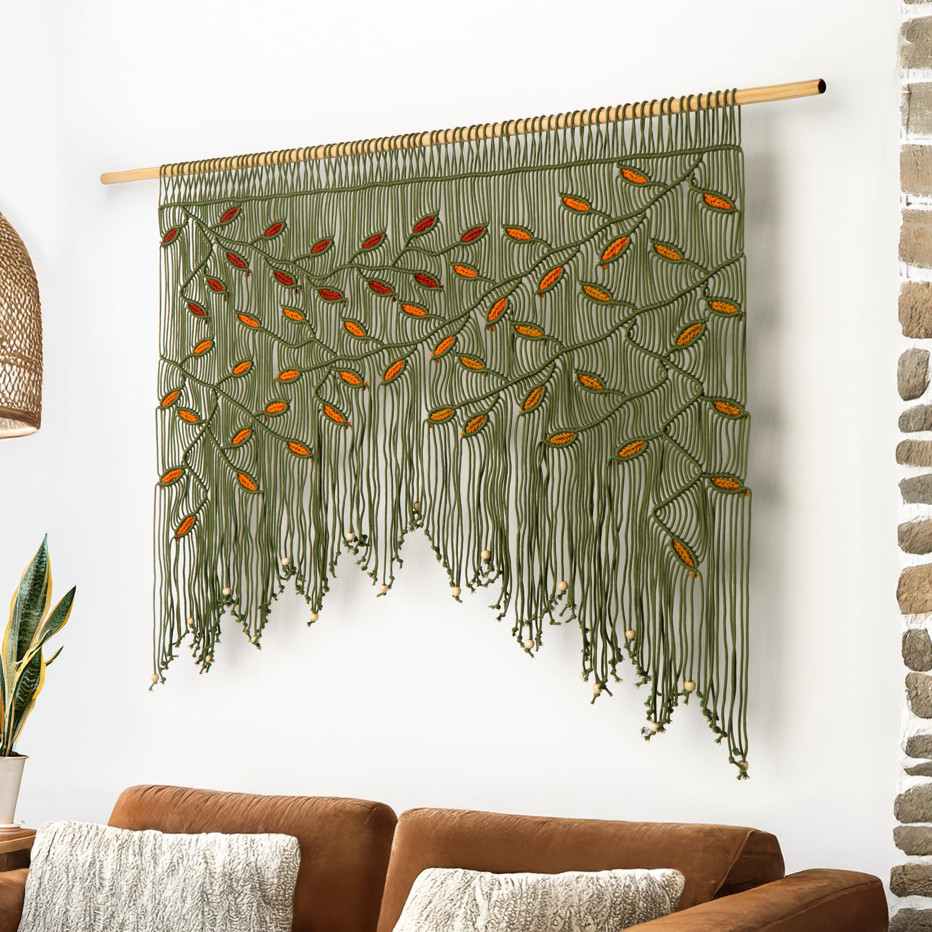 Macrame wall hanging with leaf patterns on a white wall above a bed.