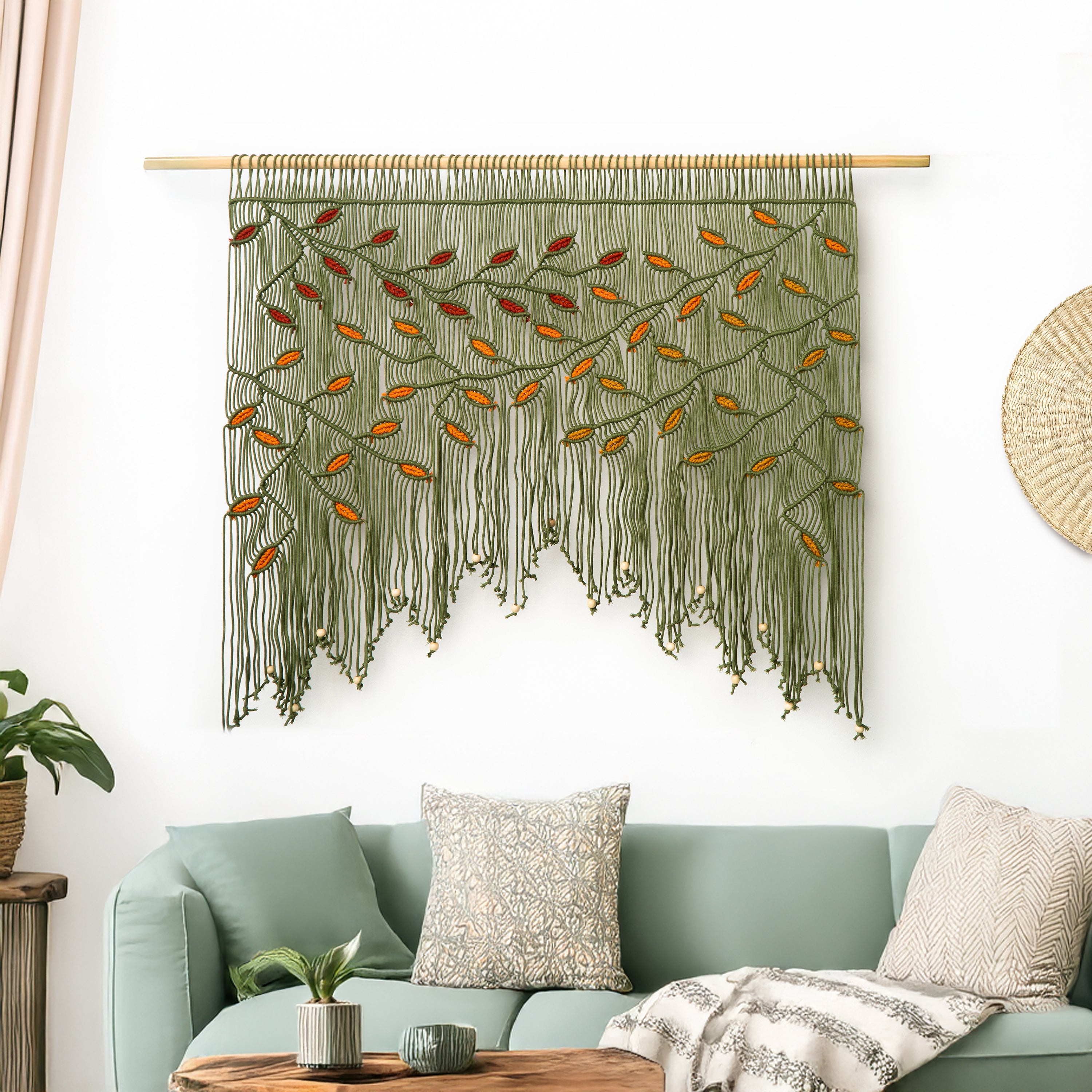 Decorative string art with leaf patterns hanging above a beige sofa with patterned cushions.
