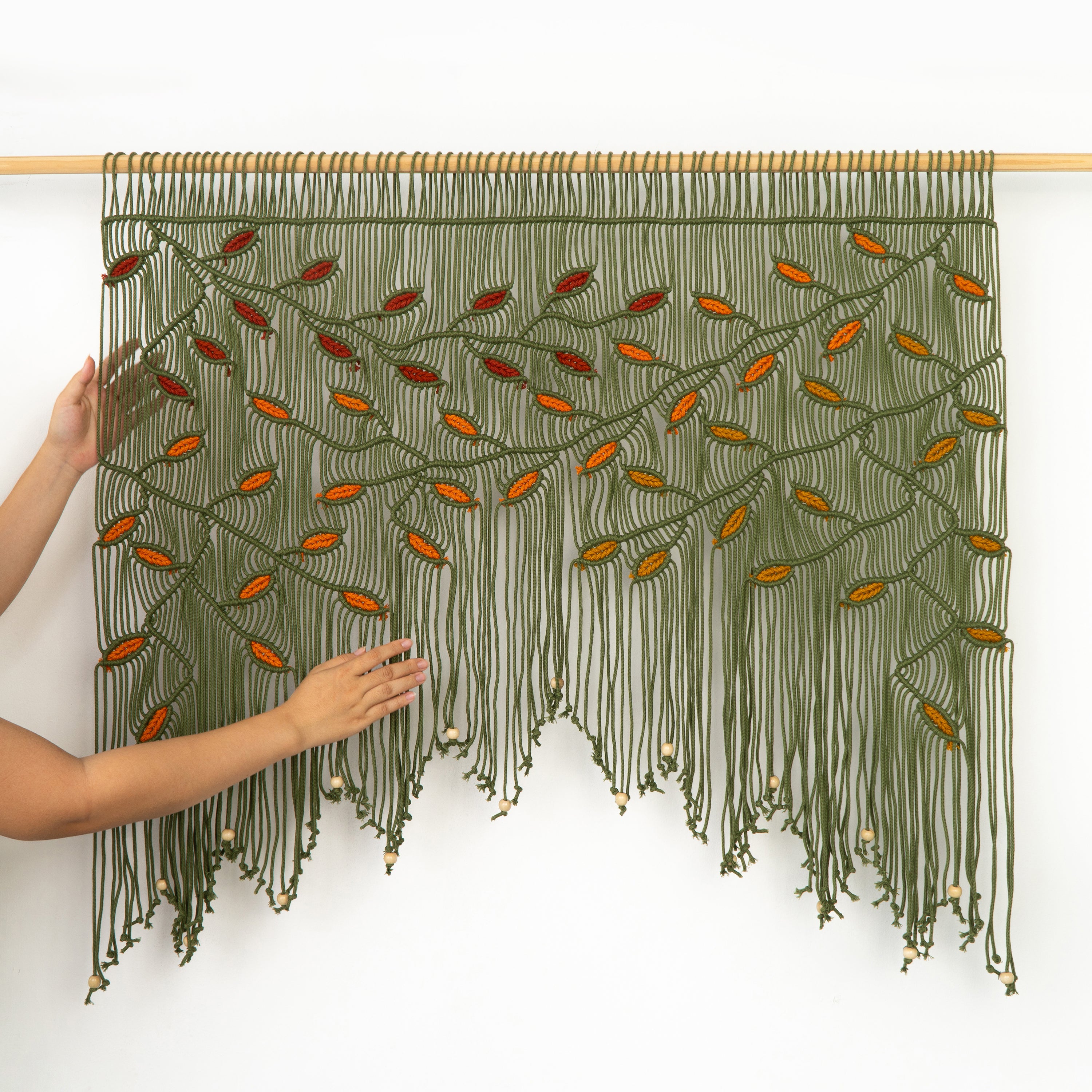 Textile art piece with green and orange pattern on a white background