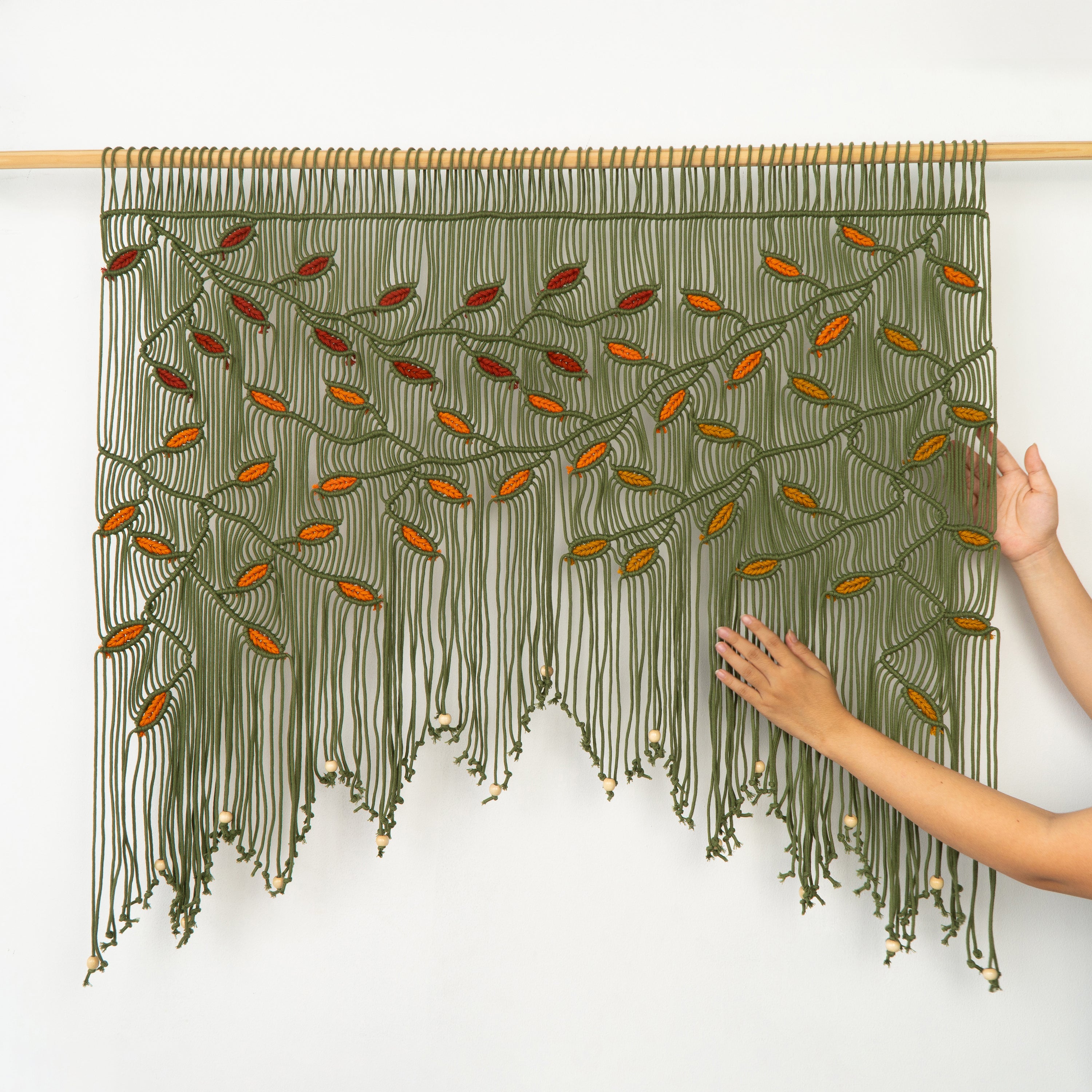 Textile art piece with green and orange pattern on a white background